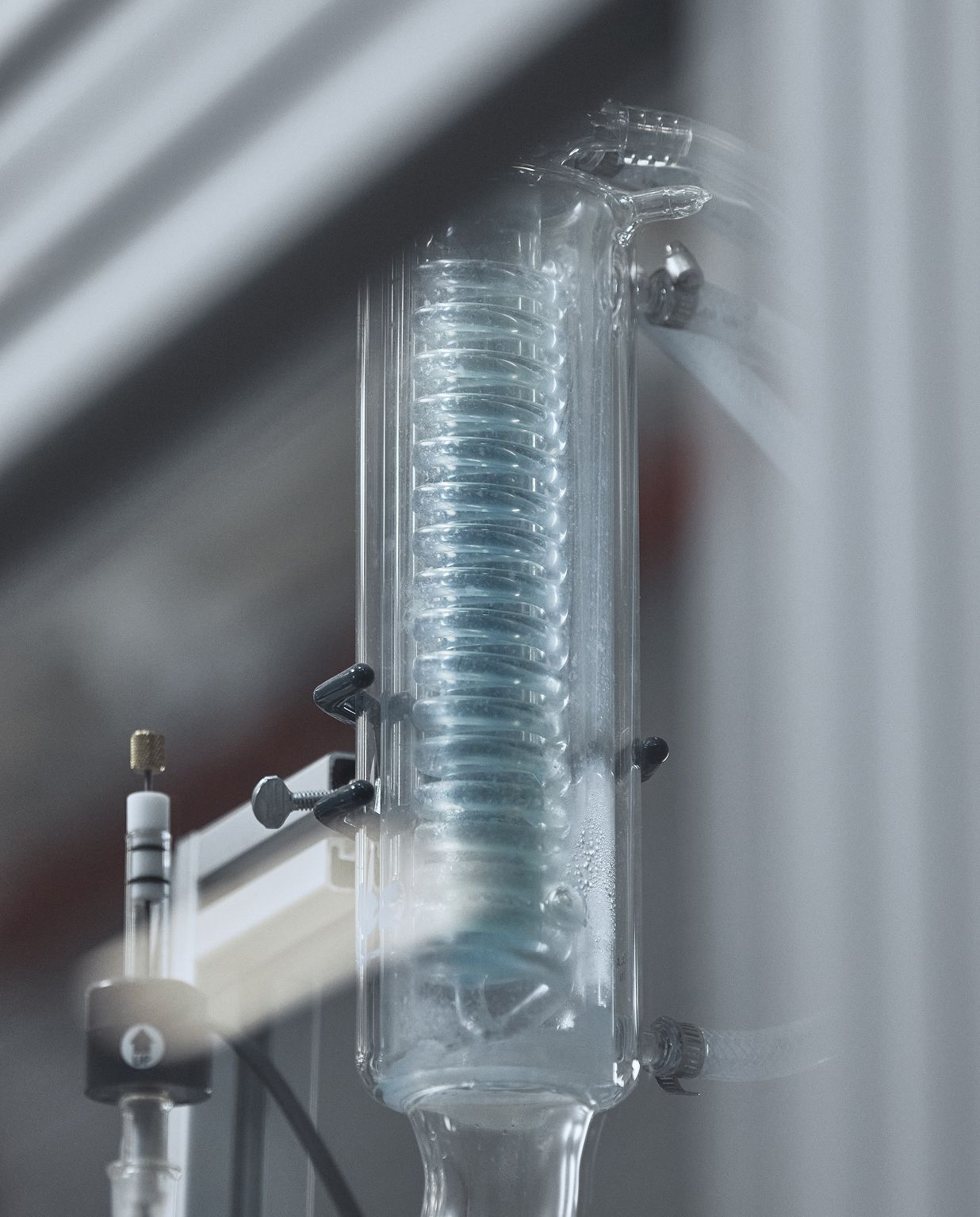 A glass condenser with a spiral coil and condensation inside.