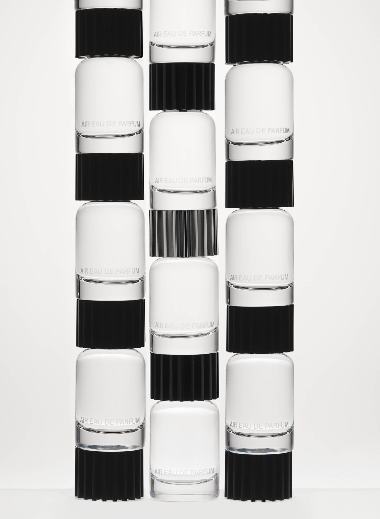 Three columns of glass fragrance bottles stacked on top of one another against a white backdrop