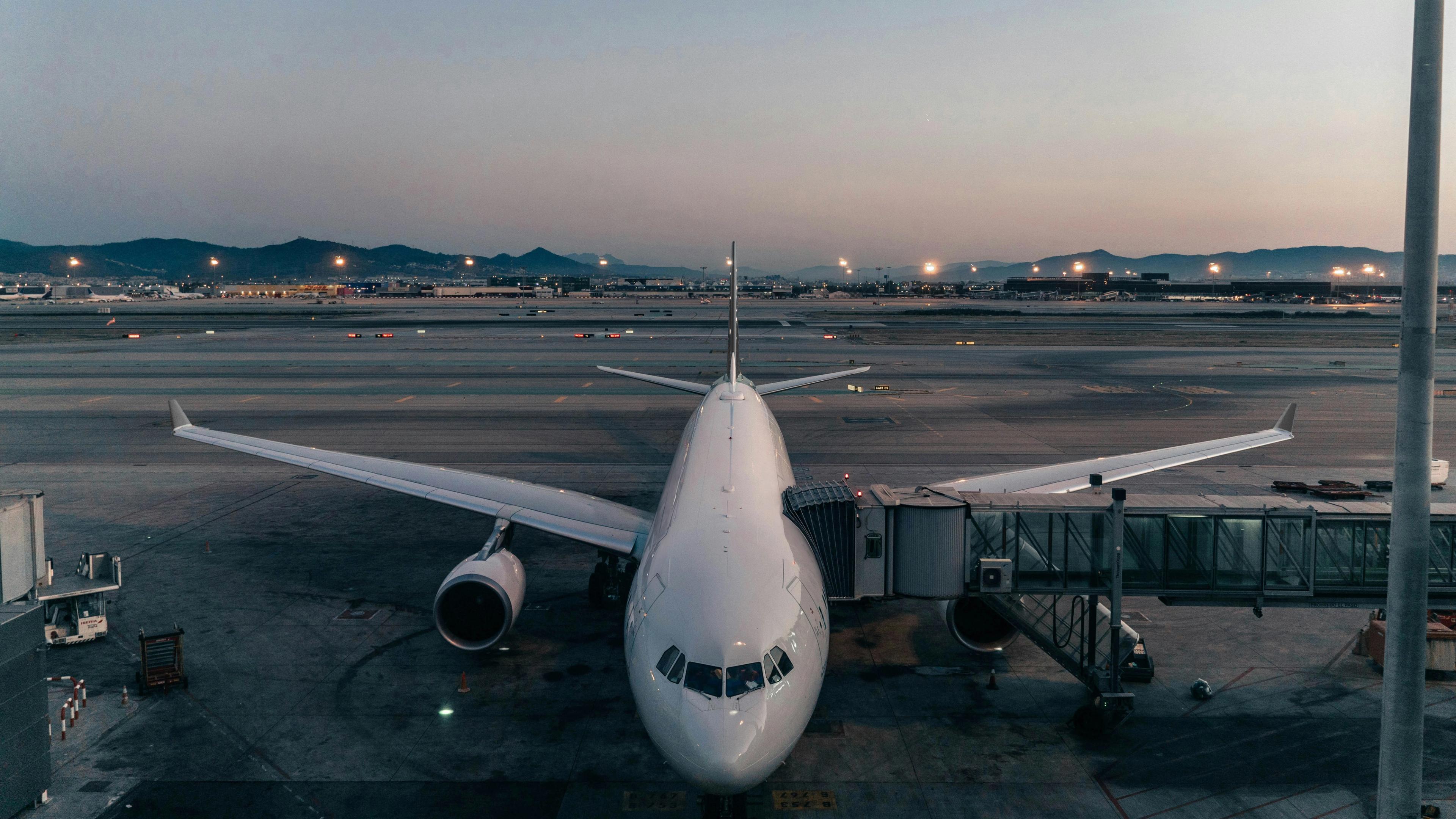 White commercial airplane parked at gate at an airport 