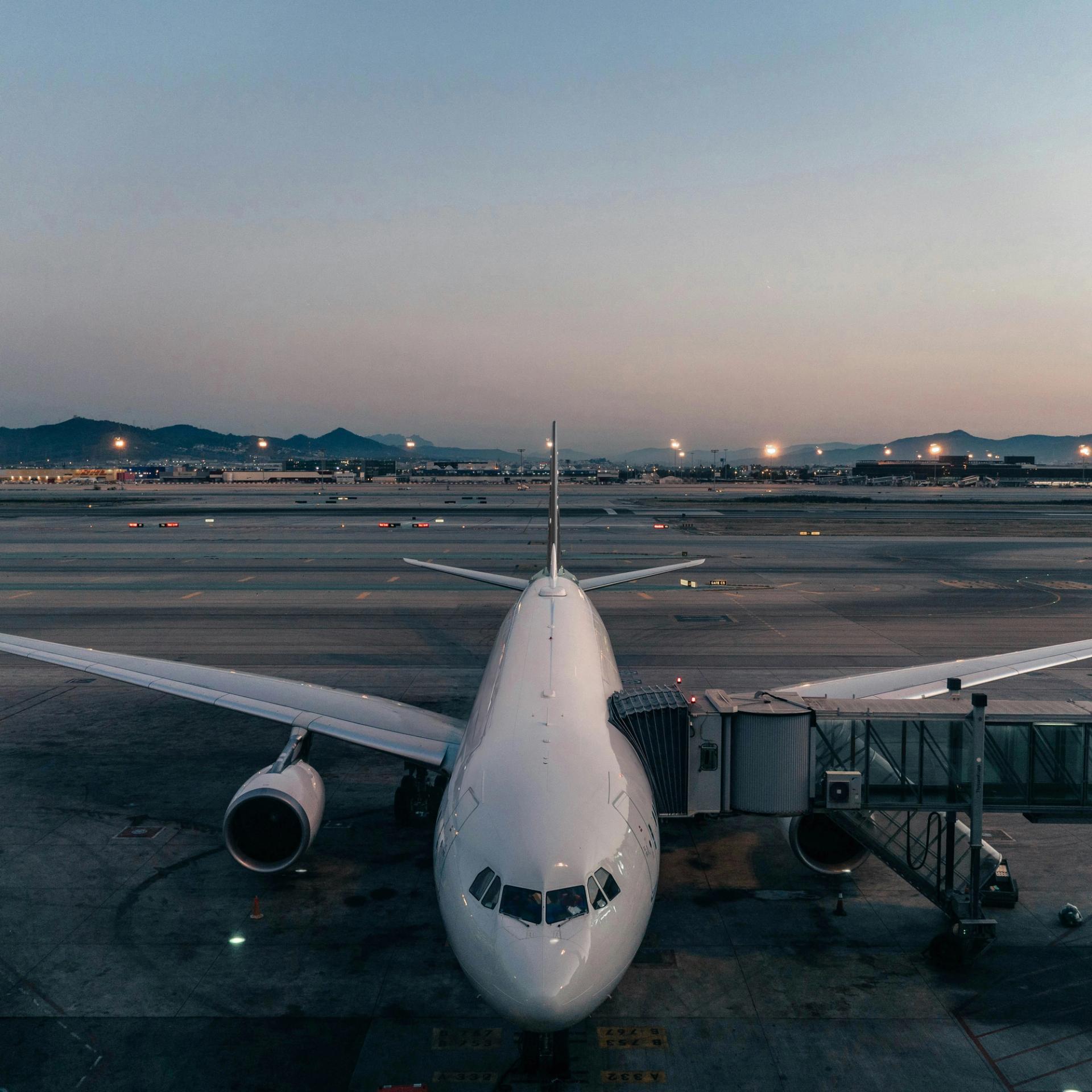 White commercial airplane parked at gate at an airport 