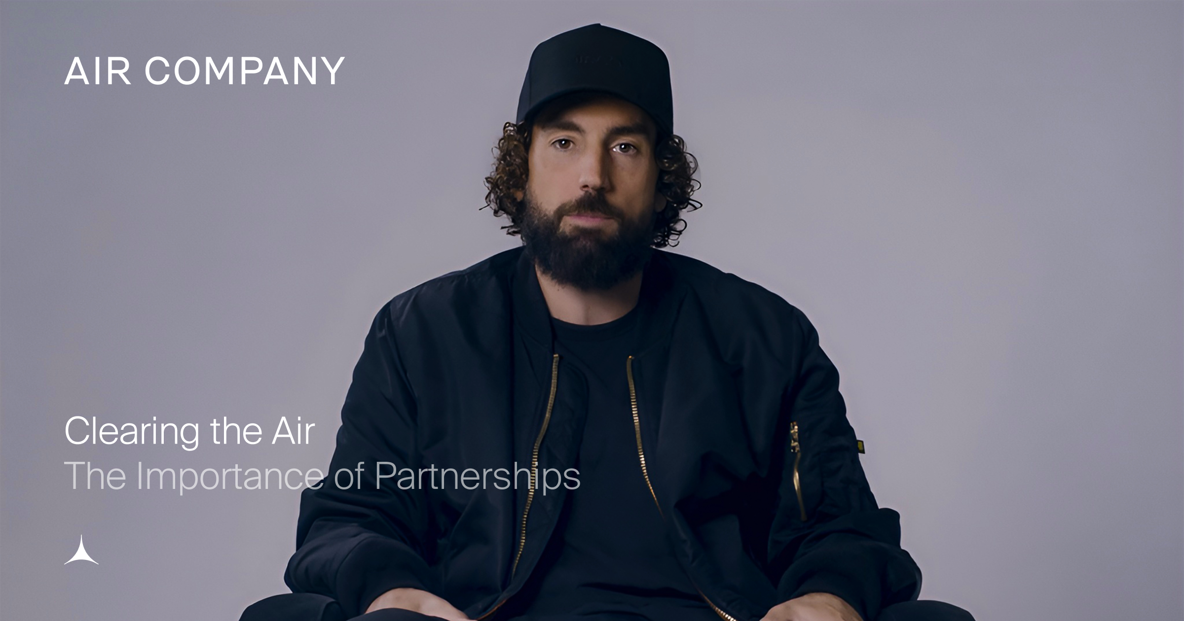 Man in a black cap and bomber jacket with a beard and curly hair looks forward. Text: AIR COMPANY, Clearing the Air, The Importance of Partnerships.