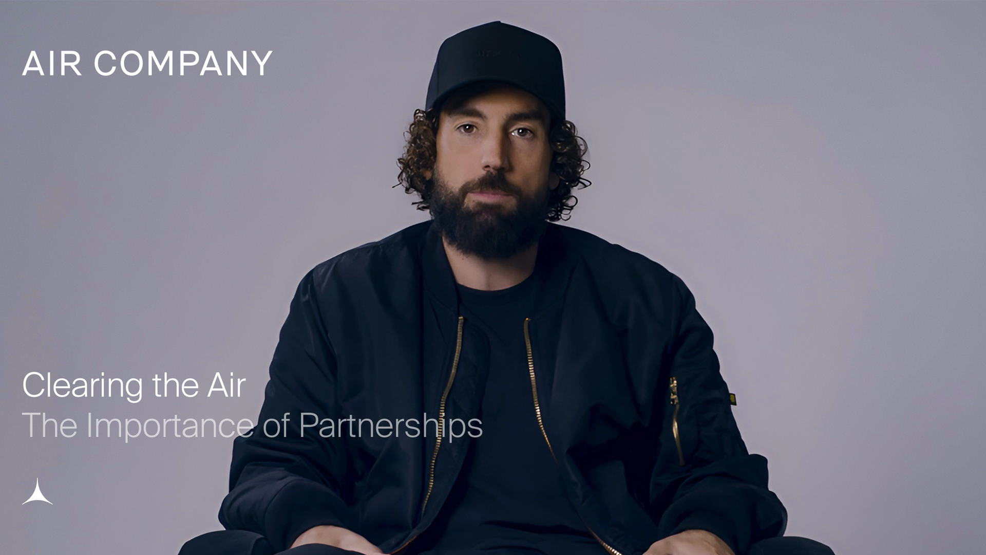 Man in a black cap and bomber jacket with a beard and curly hair looks forward. Text: AIR COMPANY, Clearing the Air, The Importance of Partnerships.