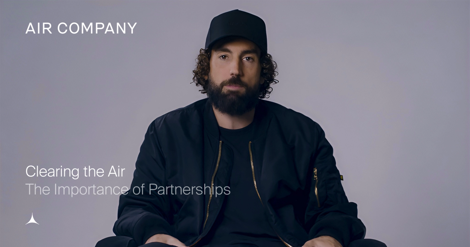Man in a black cap and bomber jacket with a beard and curly hair looks forward. Text: AIR COMPANY, Clearing the Air, The Importance of Partnerships.