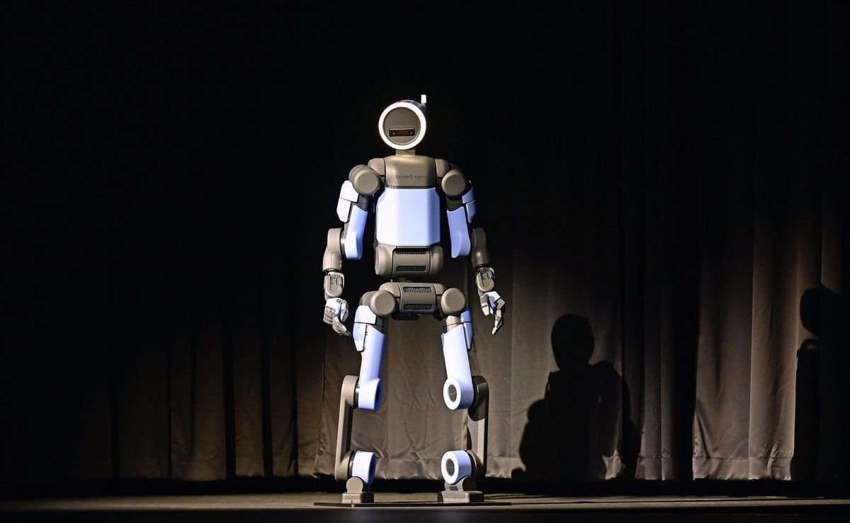 Boston Dynamics Atlas Humanoid in frontaler Ganzkörperansicht auf abgedunkelter Bühne, dramatisch ausgeleuchtet.