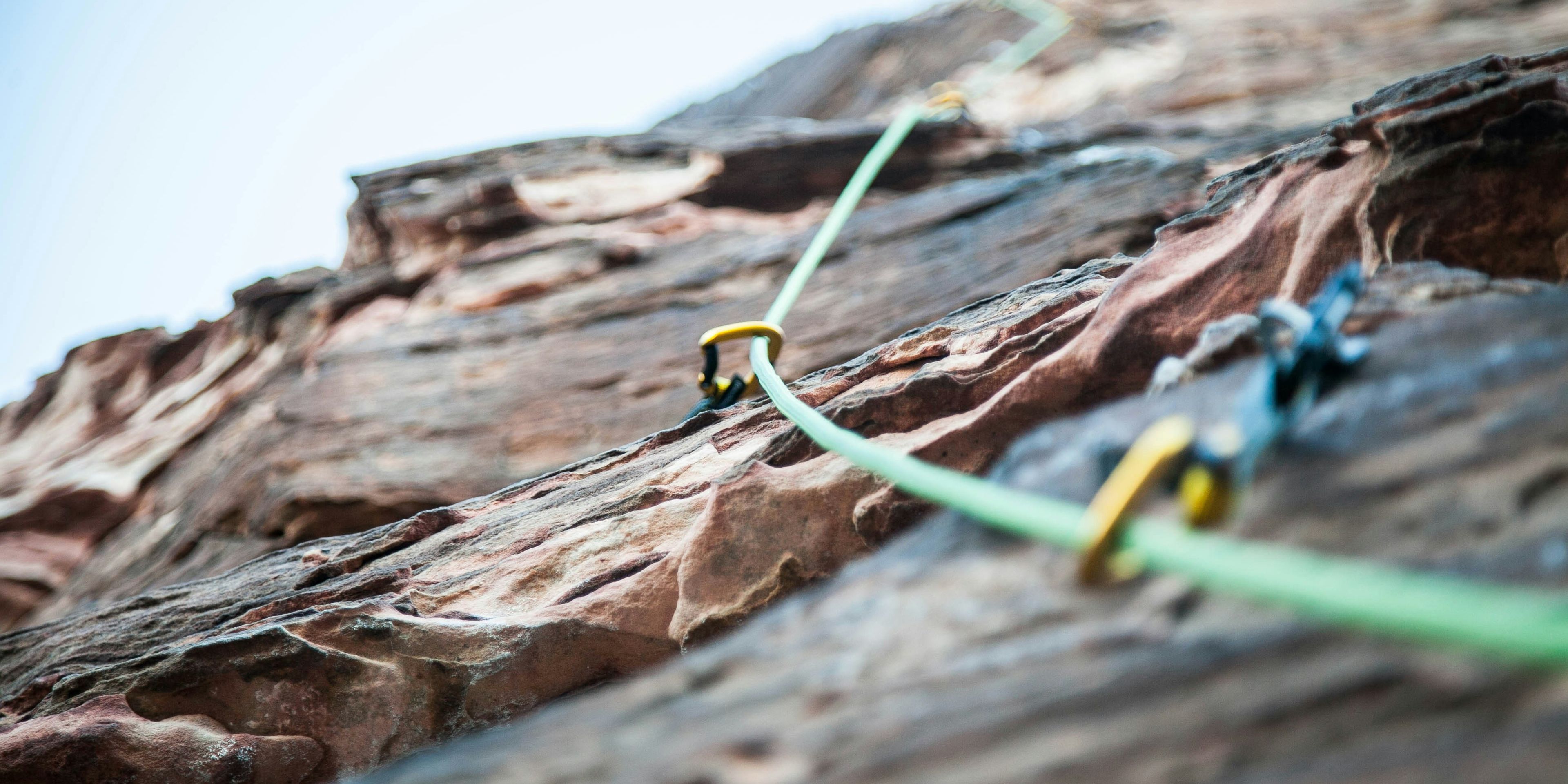 a person is climbing up a rock wall with a green rope