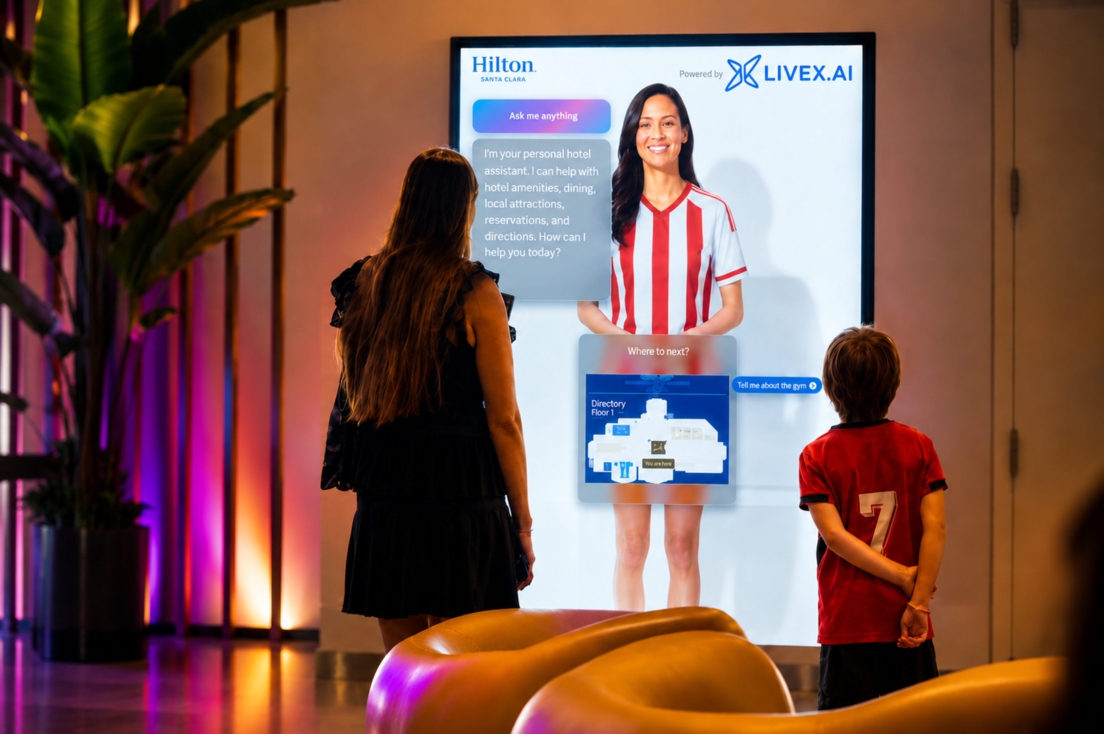 Guests interacting with a LiveX AI hotel concierge display at Hilton Santa Clara