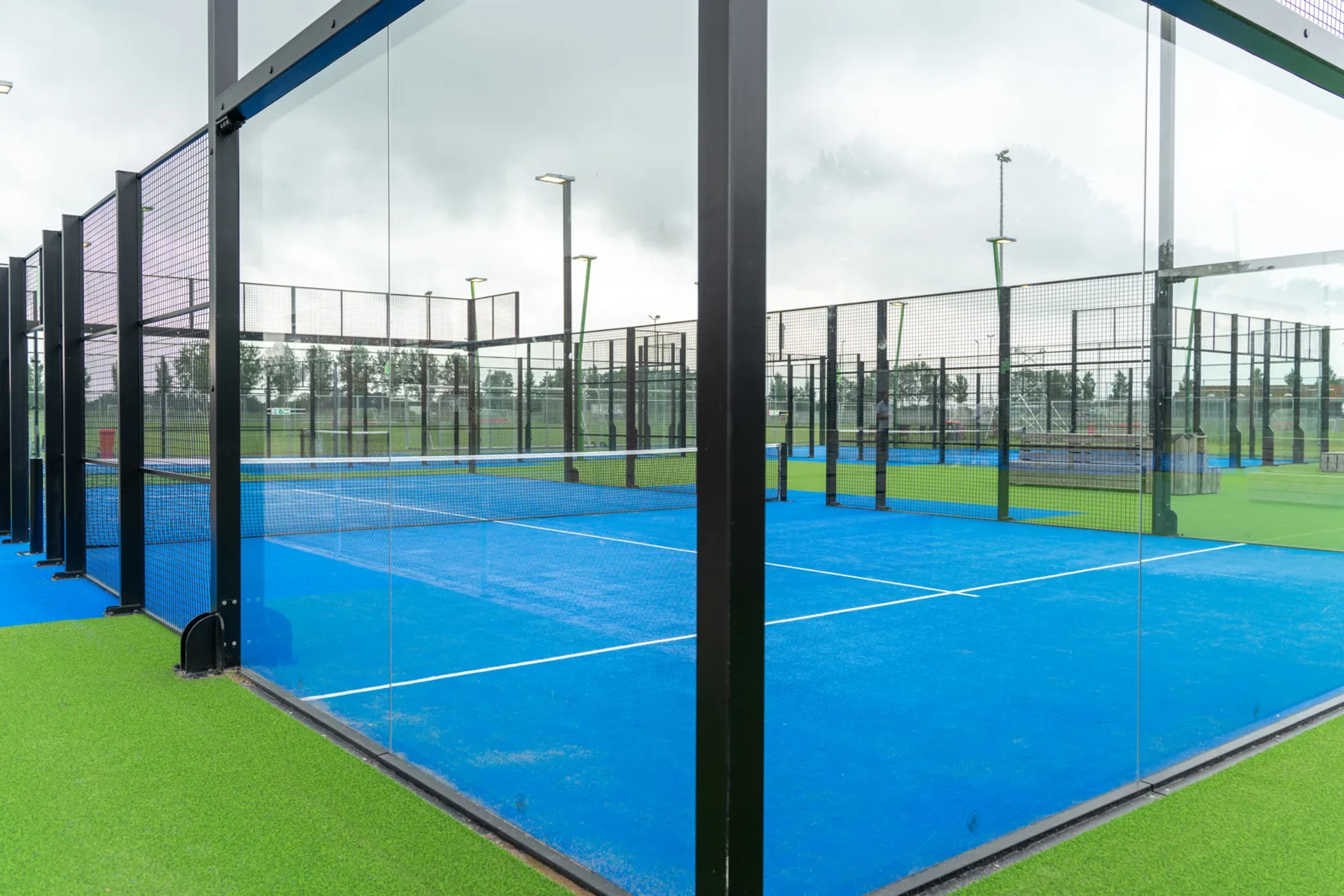 Outdoor panoramabaan met blauw kunstgras en zwart staal bij de fabriek van I-Padel