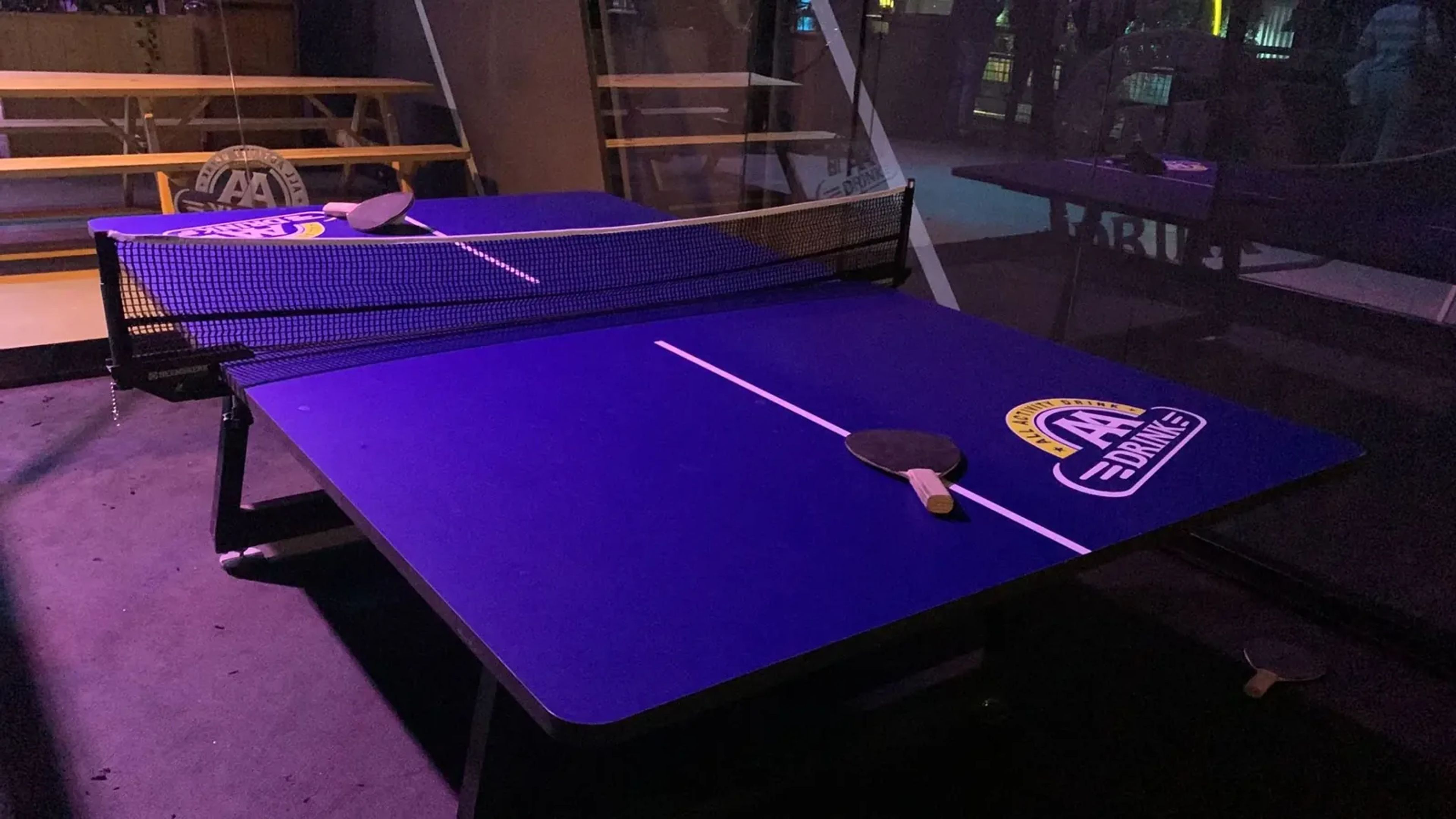 Close-up van het blauwe speelveld, het net en de batjes van de Padel Ping Pong-tafel