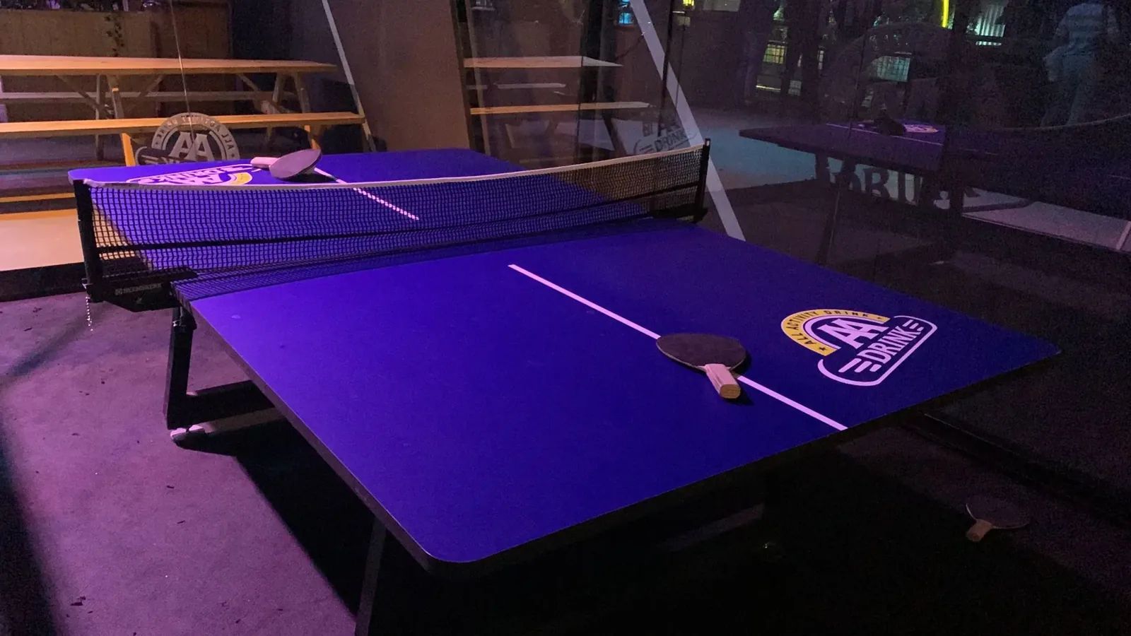 Close-up van het blauwe speelveld, het net en de batjes van de Padel Ping Pong-tafel