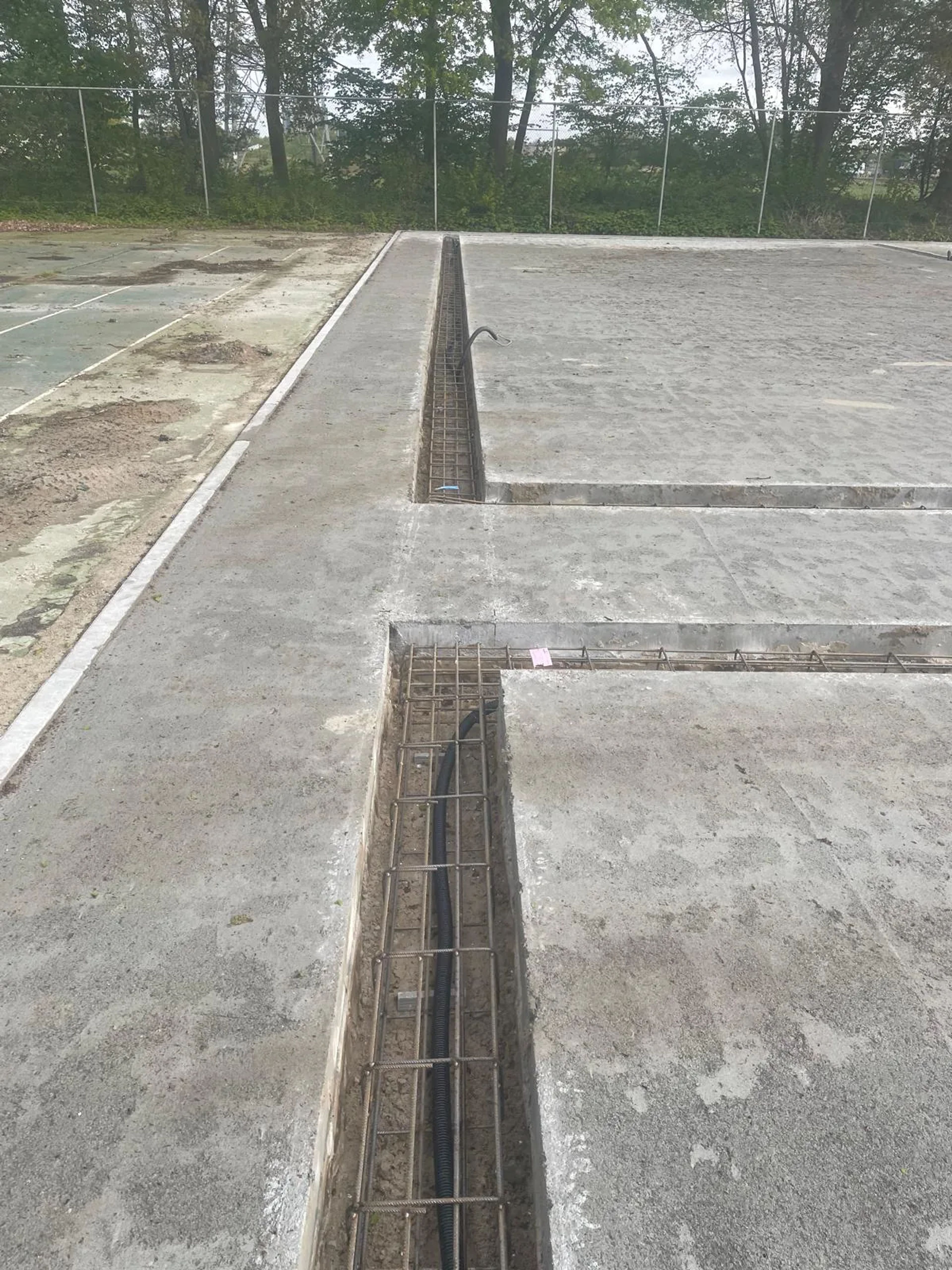 Betonnen ringfundering met drainage in grind voor een padelbaan