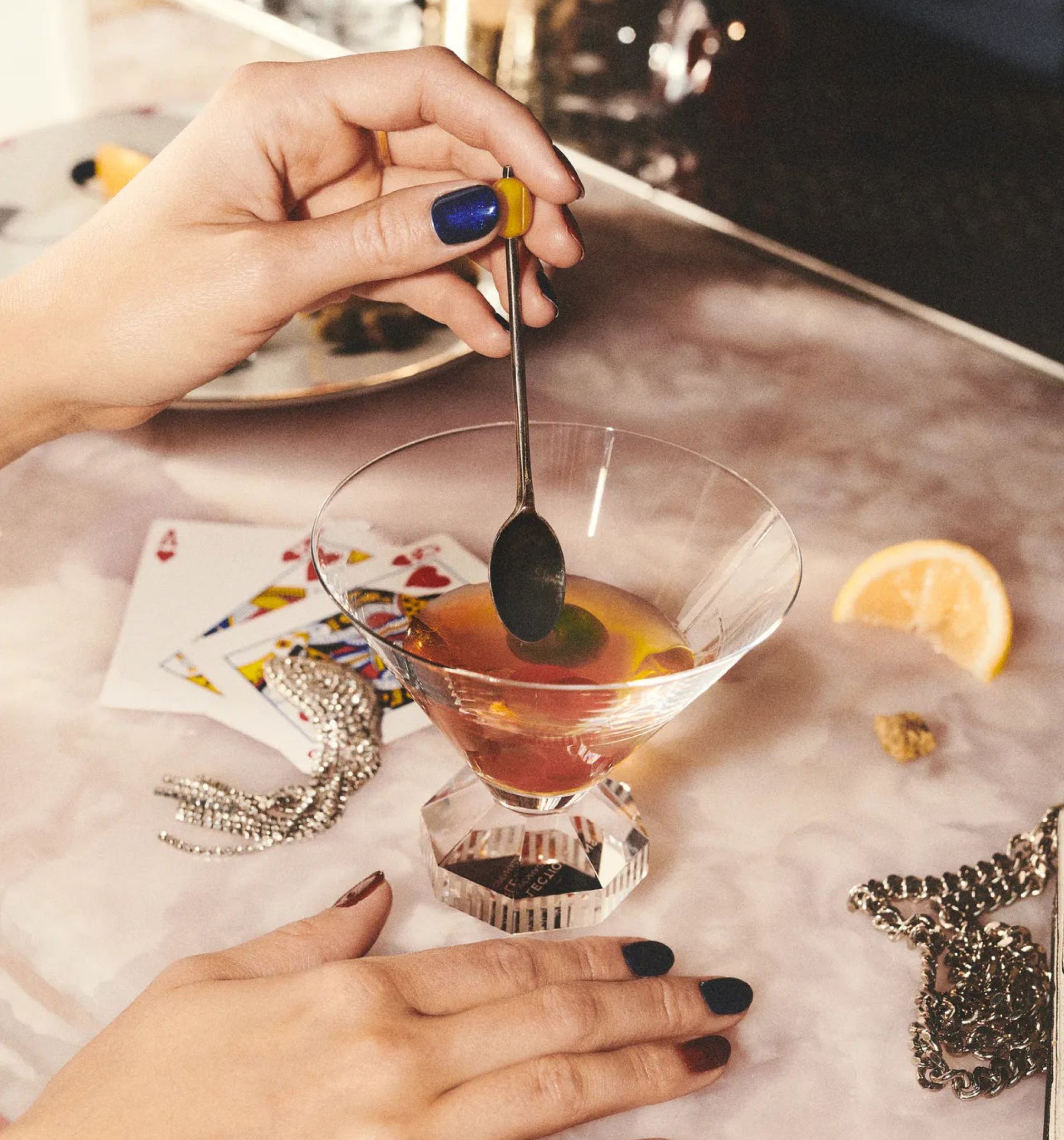 Kéz koktélolívát tart kanállal egy martinis pohár fölött