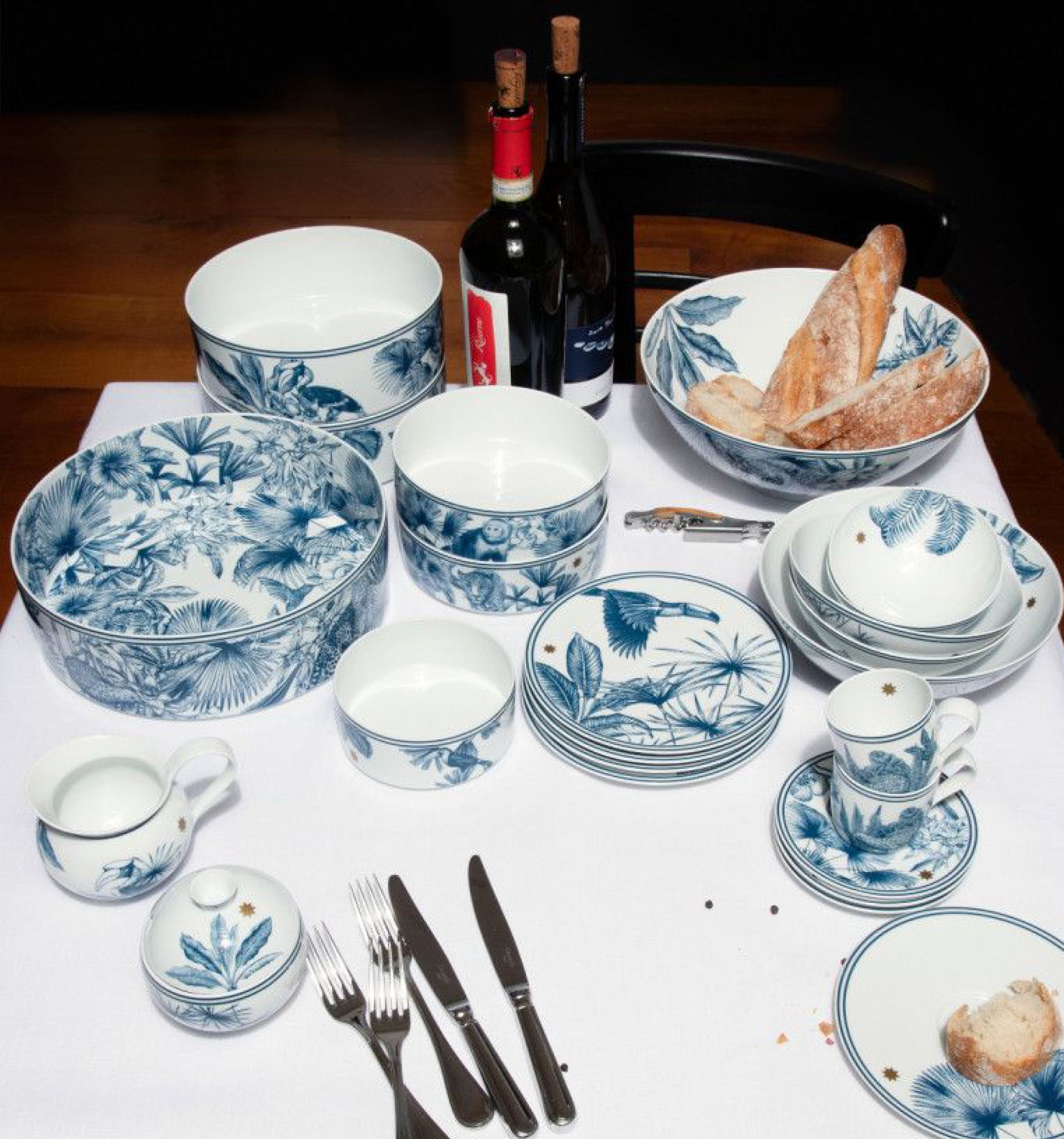 Kék növénymintás porcelán étkészlet kenyérrel, borospalackokkal és evőeszközökkel
