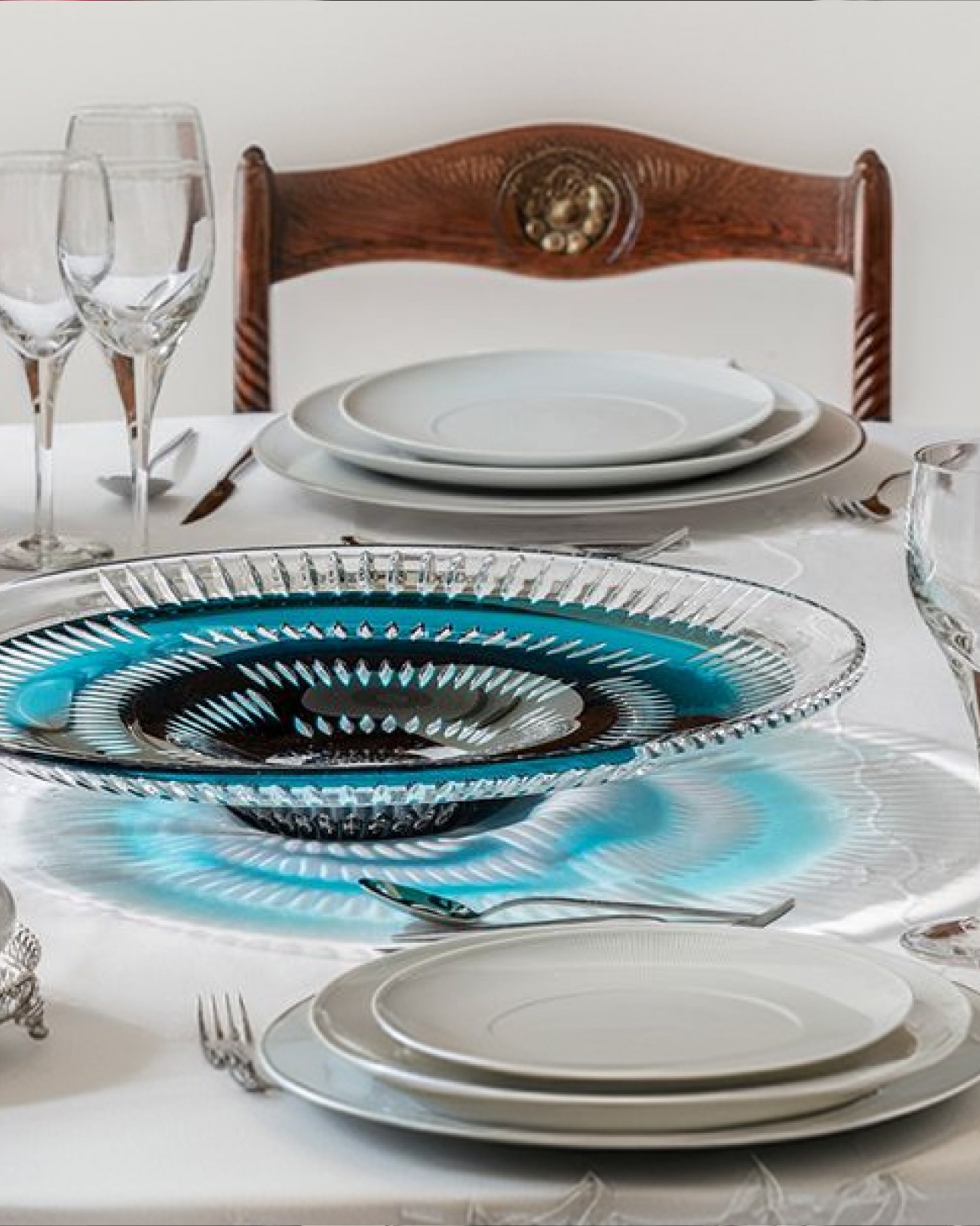 Elegánsan megterített étkezőasztal tányérokkal, poharakkal és üvegtállal