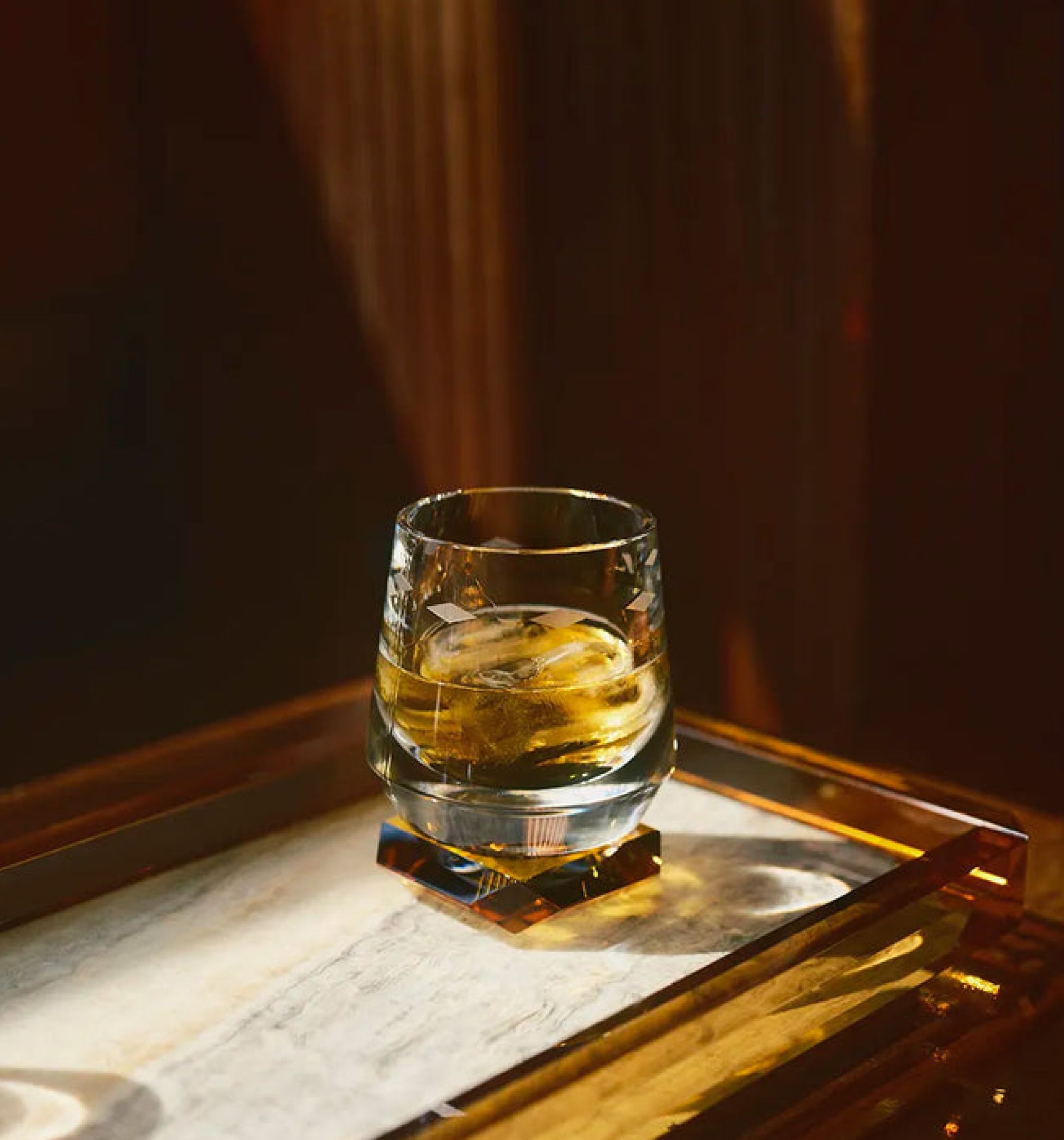 Whisky jéggel egy üvegpohárban, márványlapos tálcán