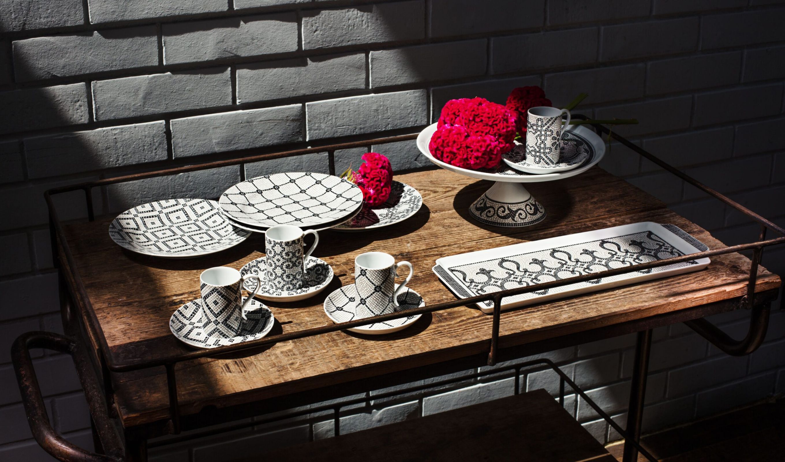Mintás porceláncsészék és tányérok fa tálalókocsin, piros virágokkal