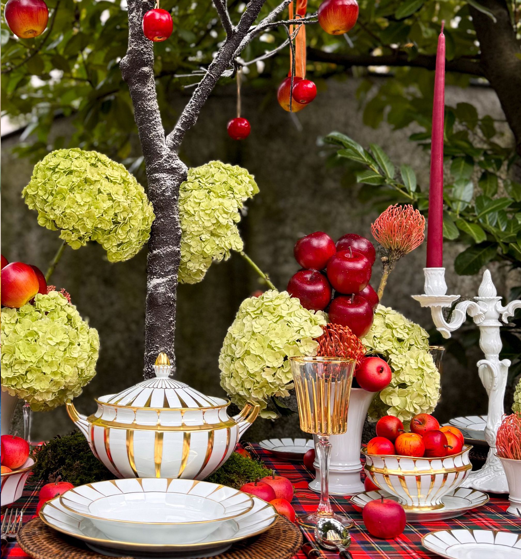 Almákkal és hortenziákkal díszített ünnepi asztal porcelán étkészlettel és gyertyával