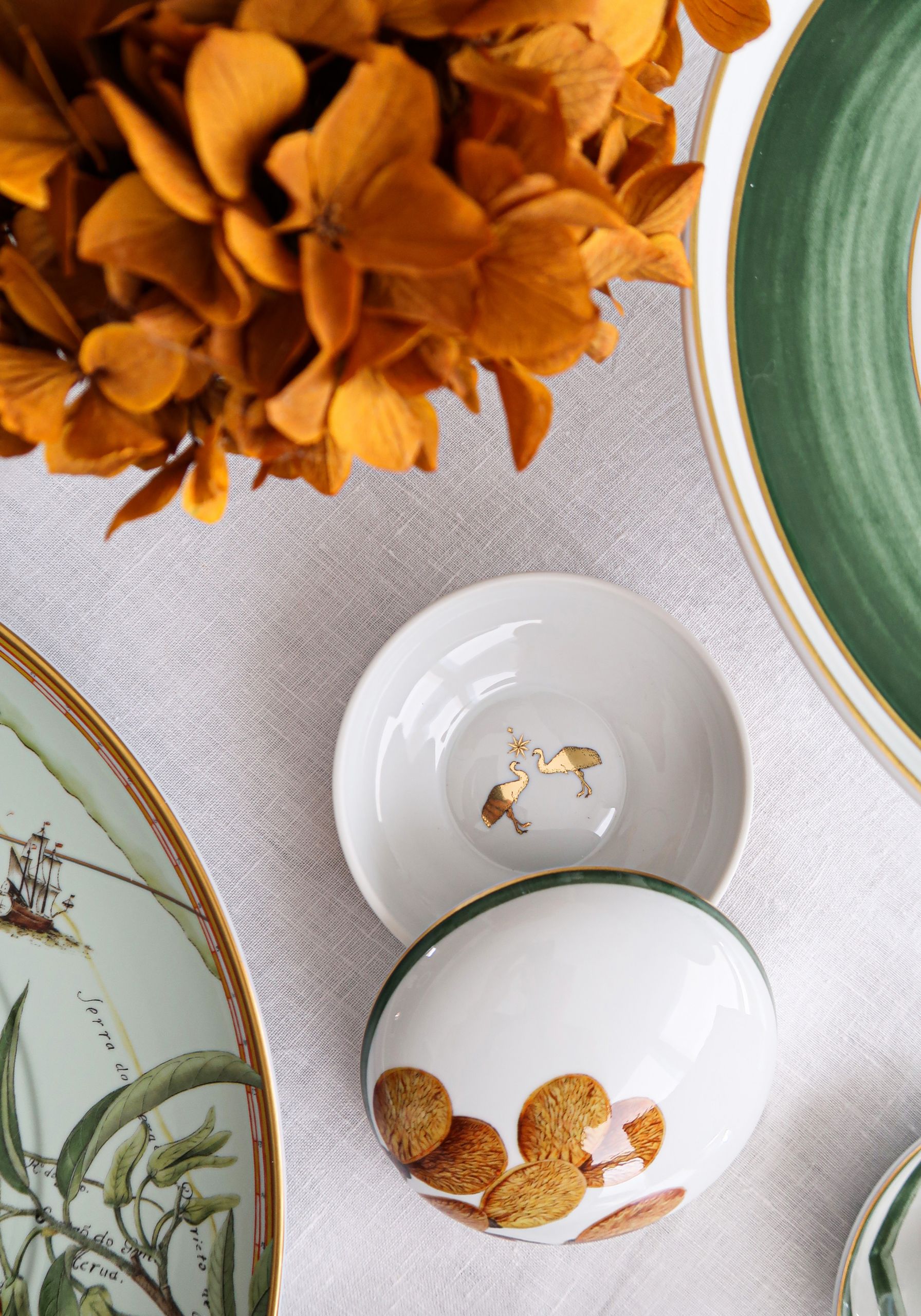 Mintás porcelántálak és narancssárga virágok terített asztalon