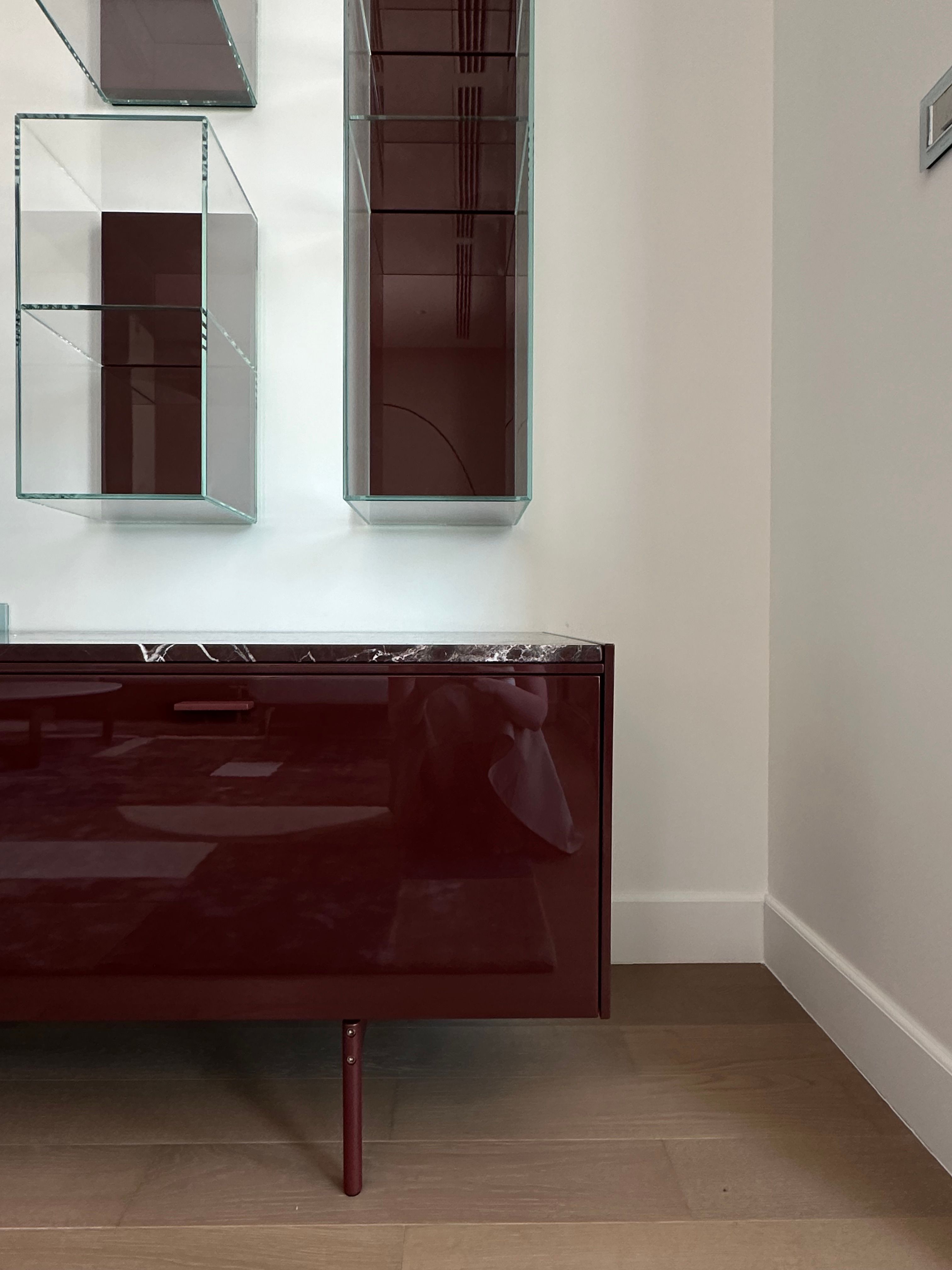 Bordó szekrény üvegpolcokkal egy modern szoba falán