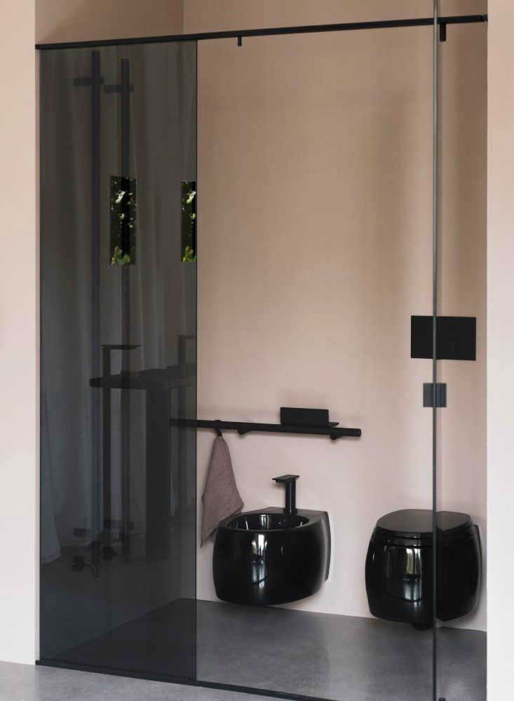 Üvegfalú fürdőszoba fekete zuhannyal, mosdóval és WC-vel