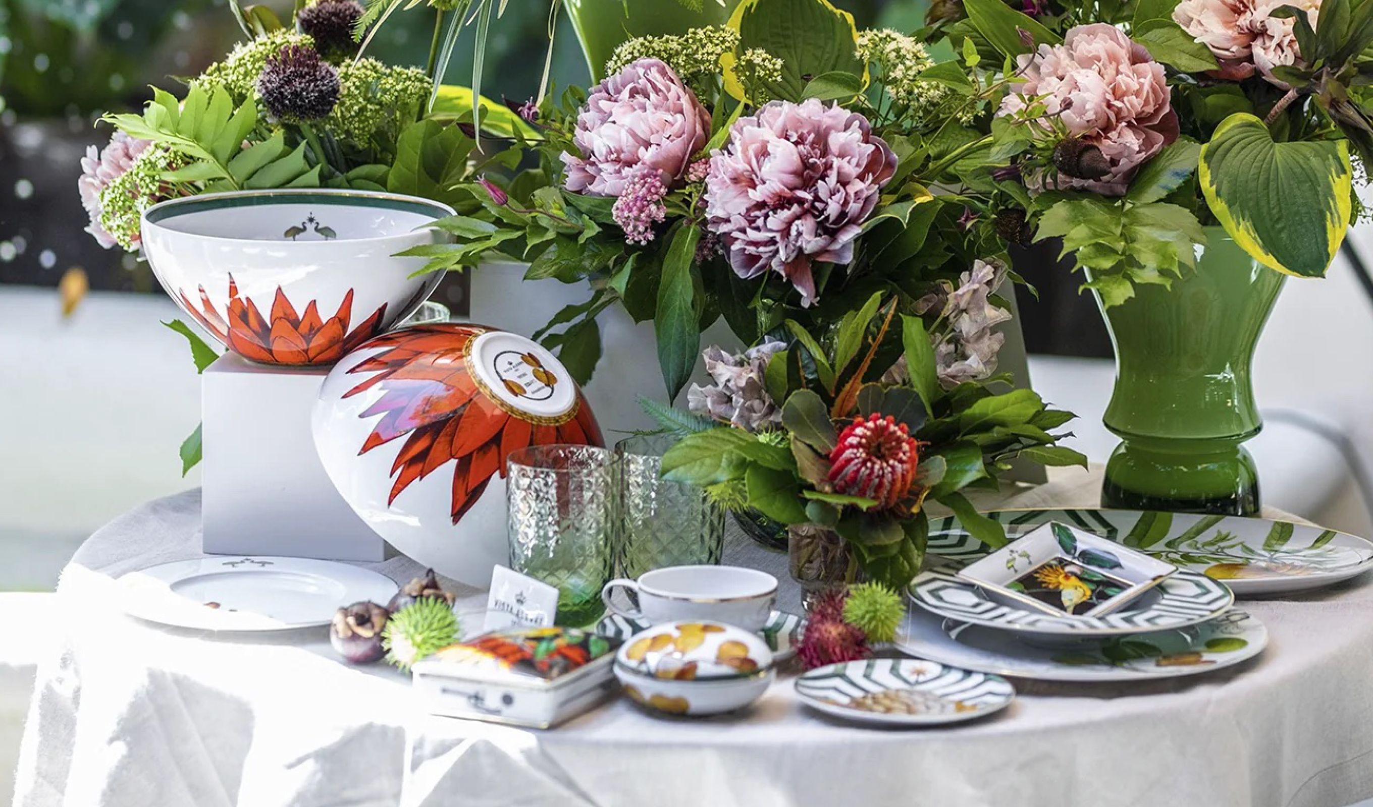 Virágcsokrokkal és mintás porcelán étkészlettel megterített asztal