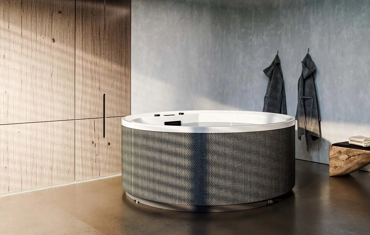 Kerek pezsgőfürdő modern wellnesshelyiségben, mellette köntösök és törölközők