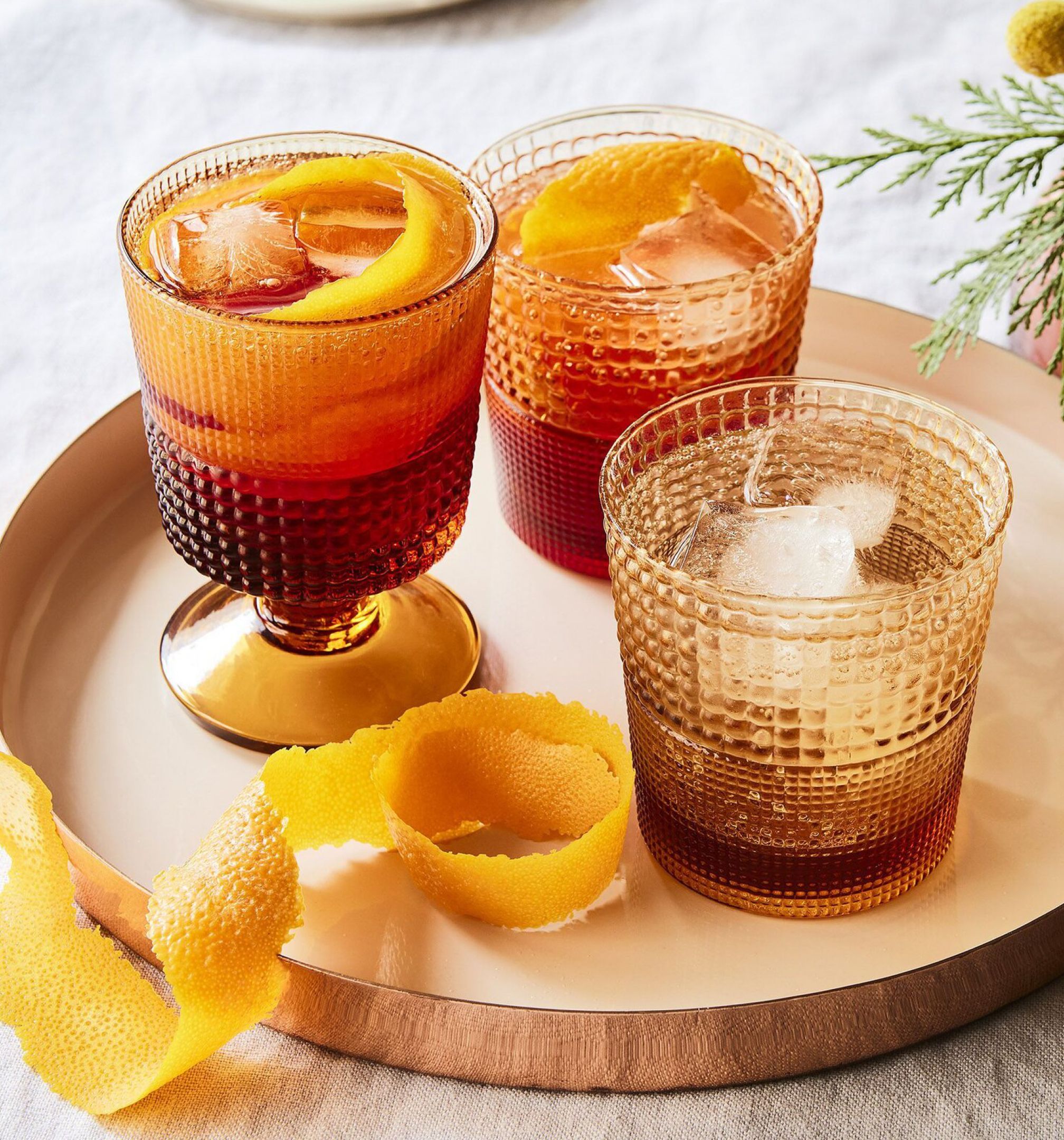 Három jeges koktél citrusos díszítéssel egy tálcán