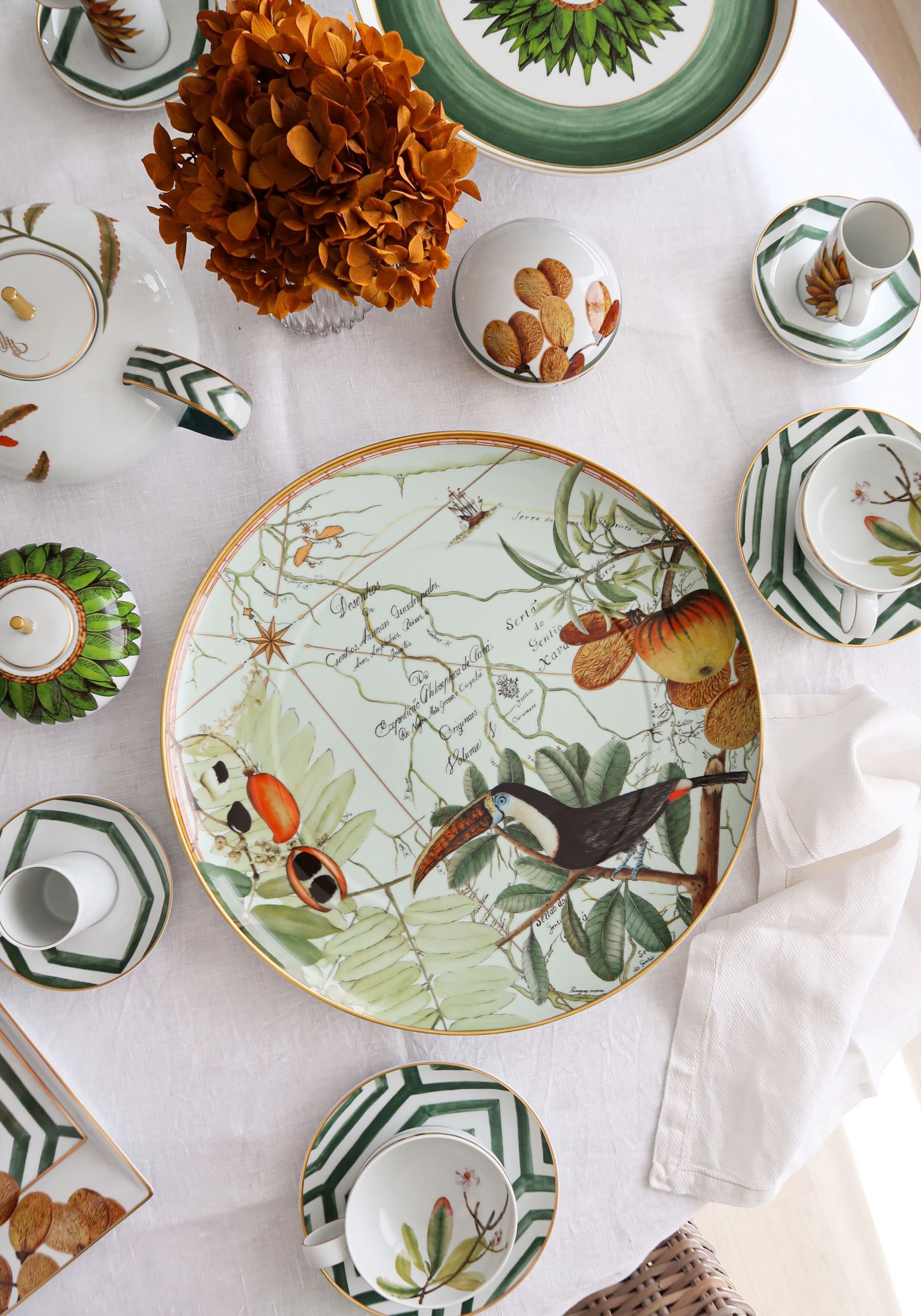 Trópusi mintás porcelán étkészlet és szárított virág terített asztalon
