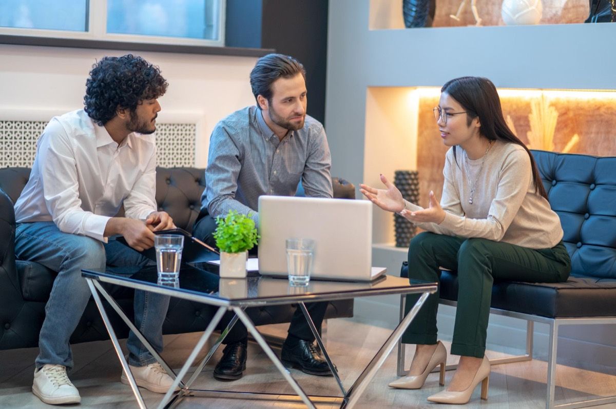 Three colleagues talking through a problem around a laptop.