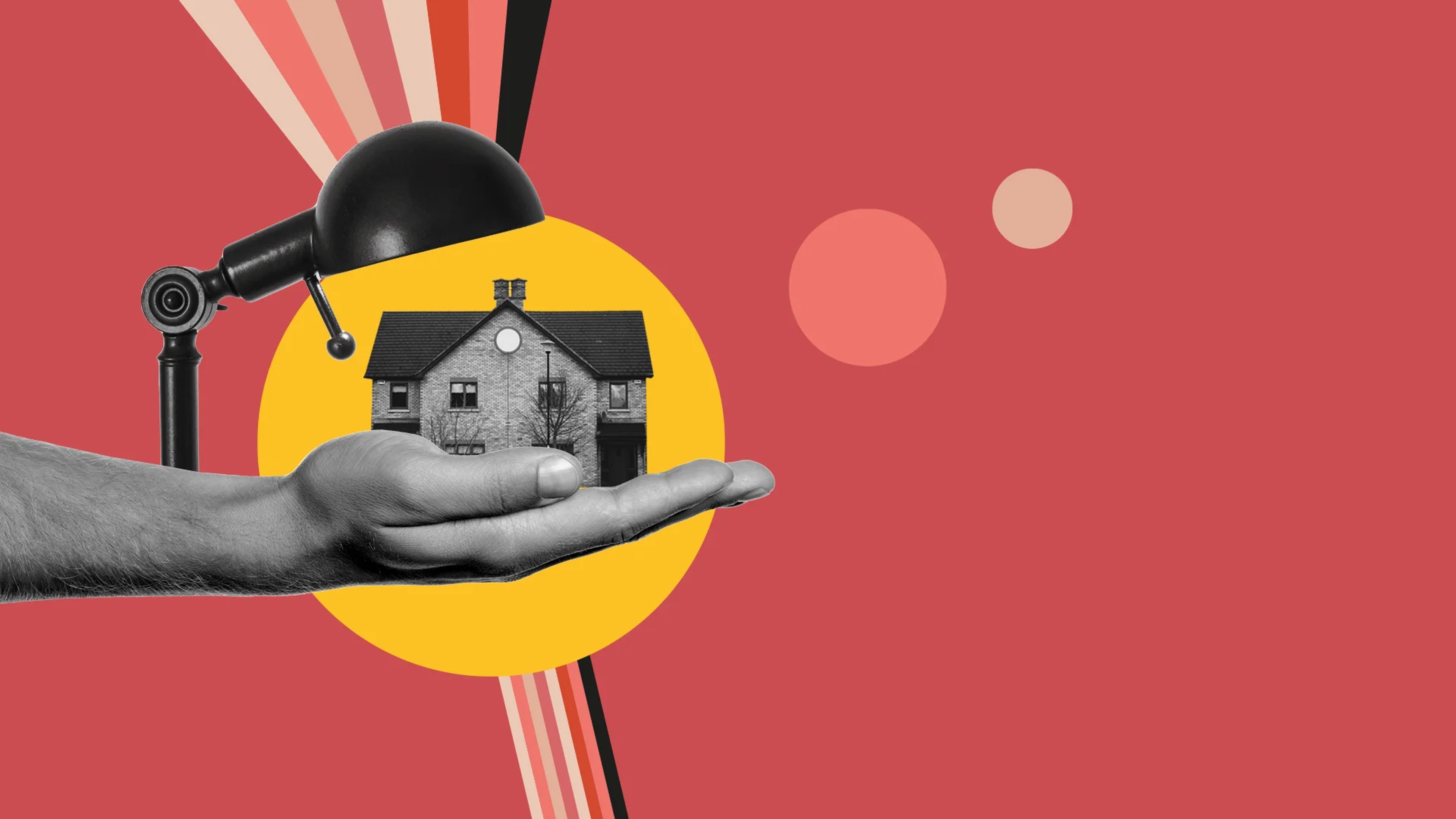 Hand holding a house, with a lamp shining over it. 