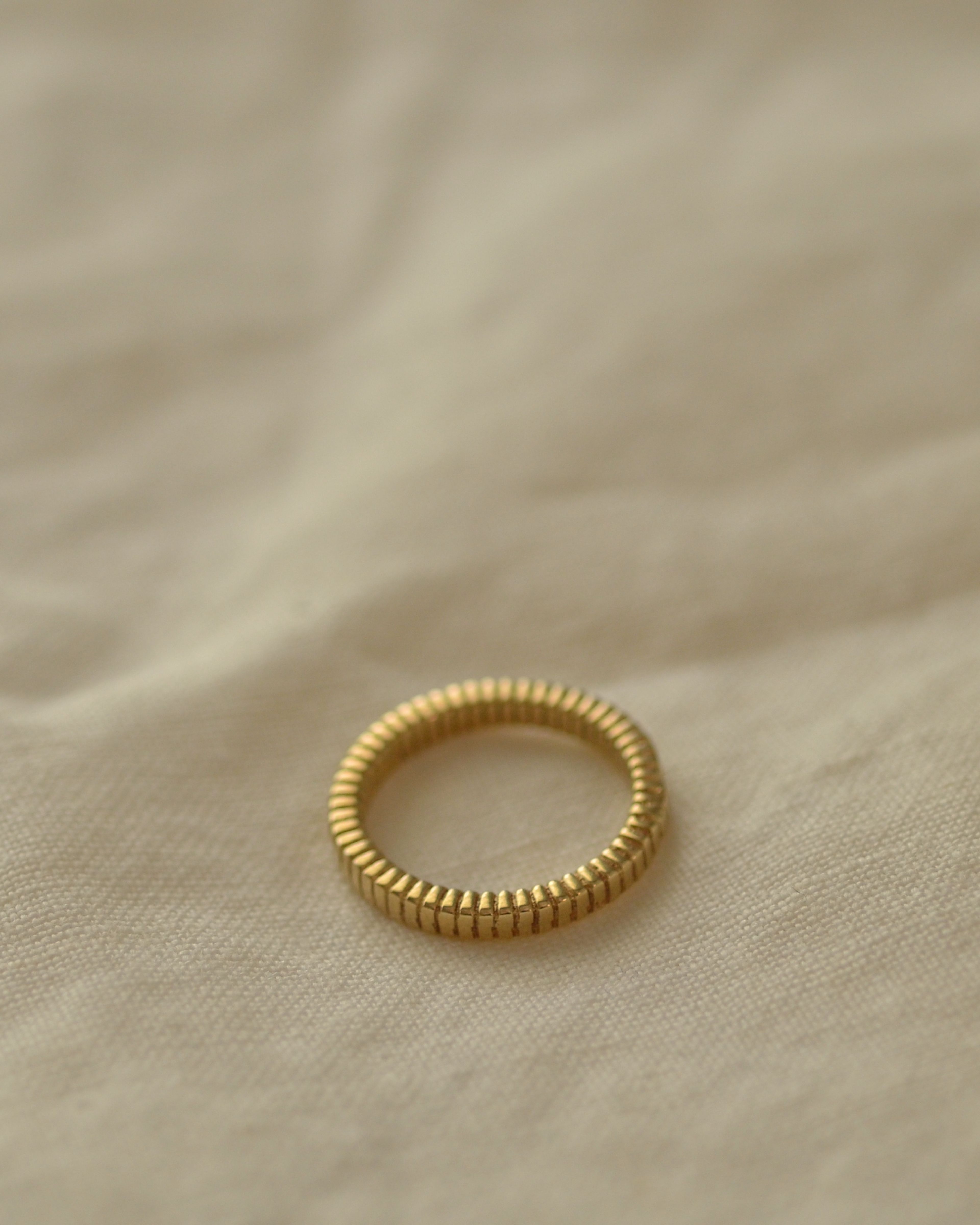 Solid gold fluted ribbed ring texture handmade on cream linen 