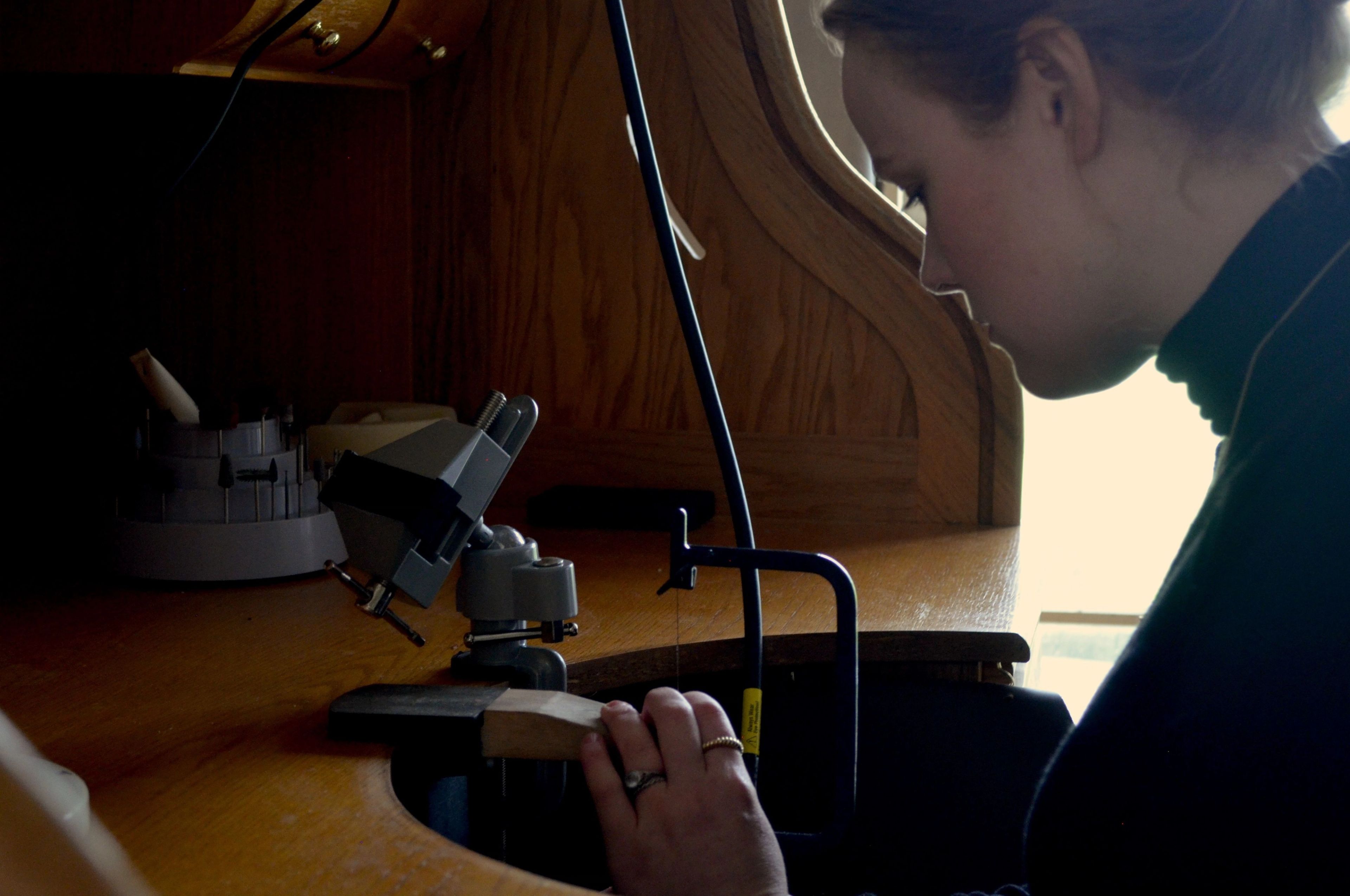 A woman, Laura, works on a ring at a work bench