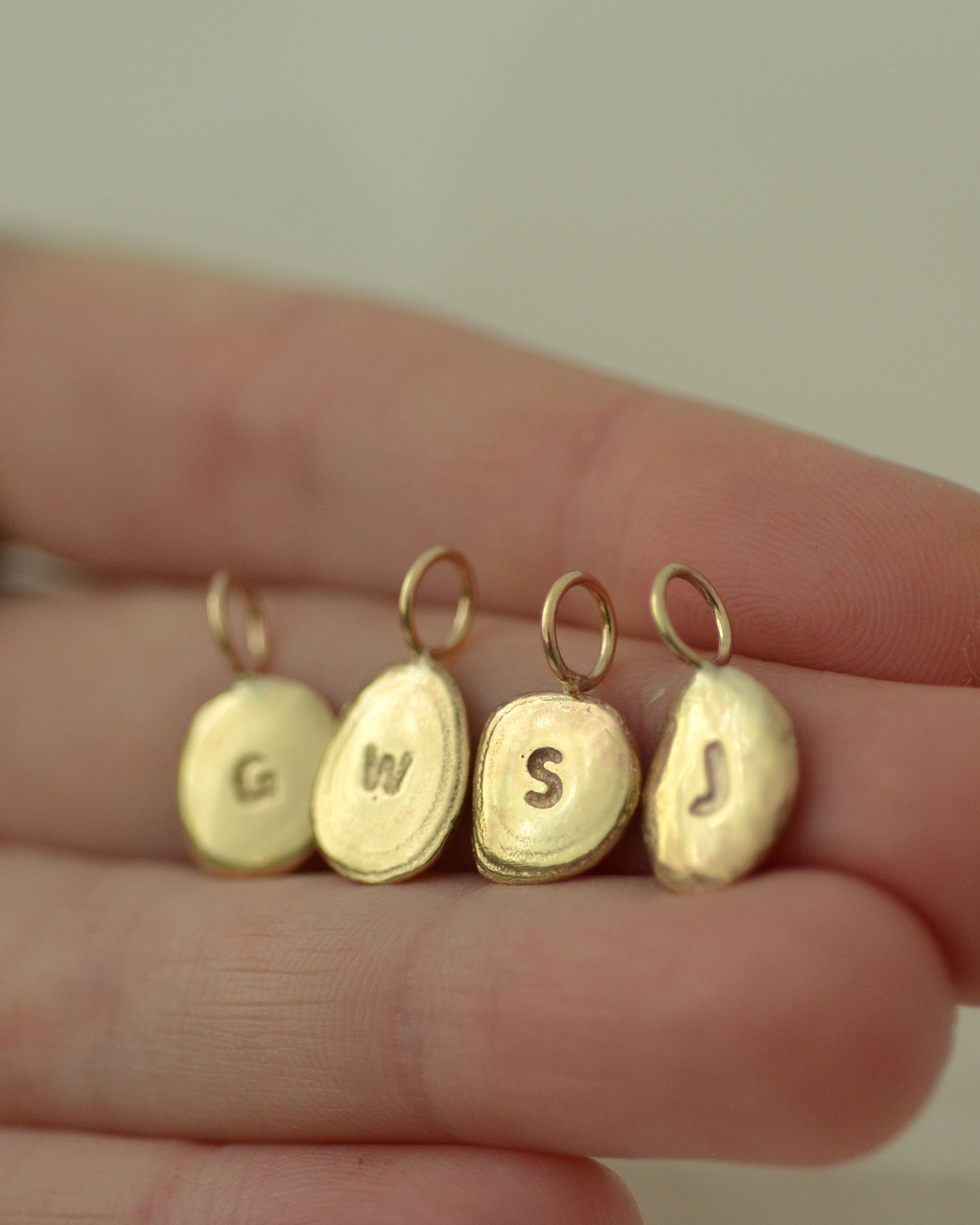 Group of gold pebble pendants held on hand