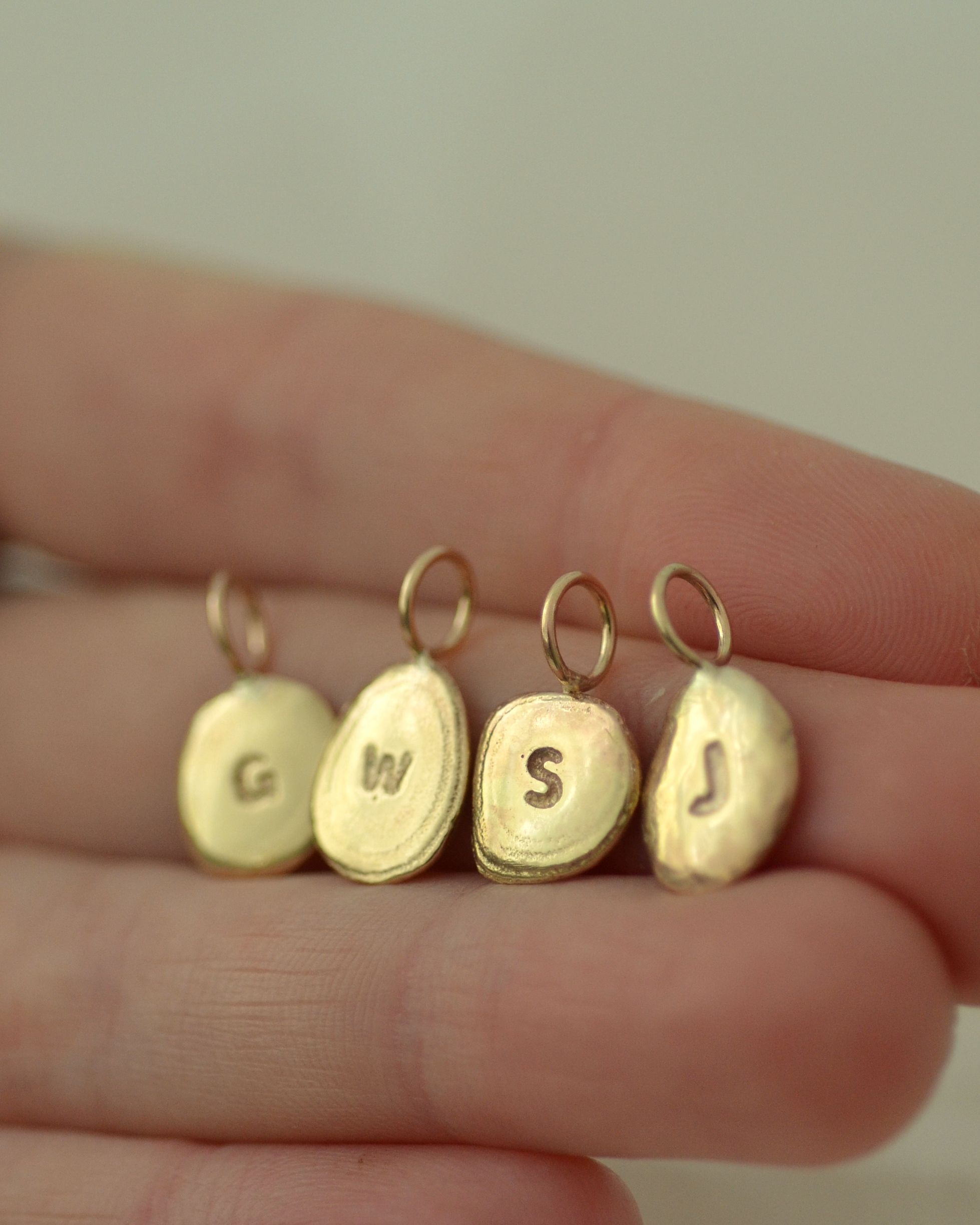 Group of gold pebble pendants held on hand