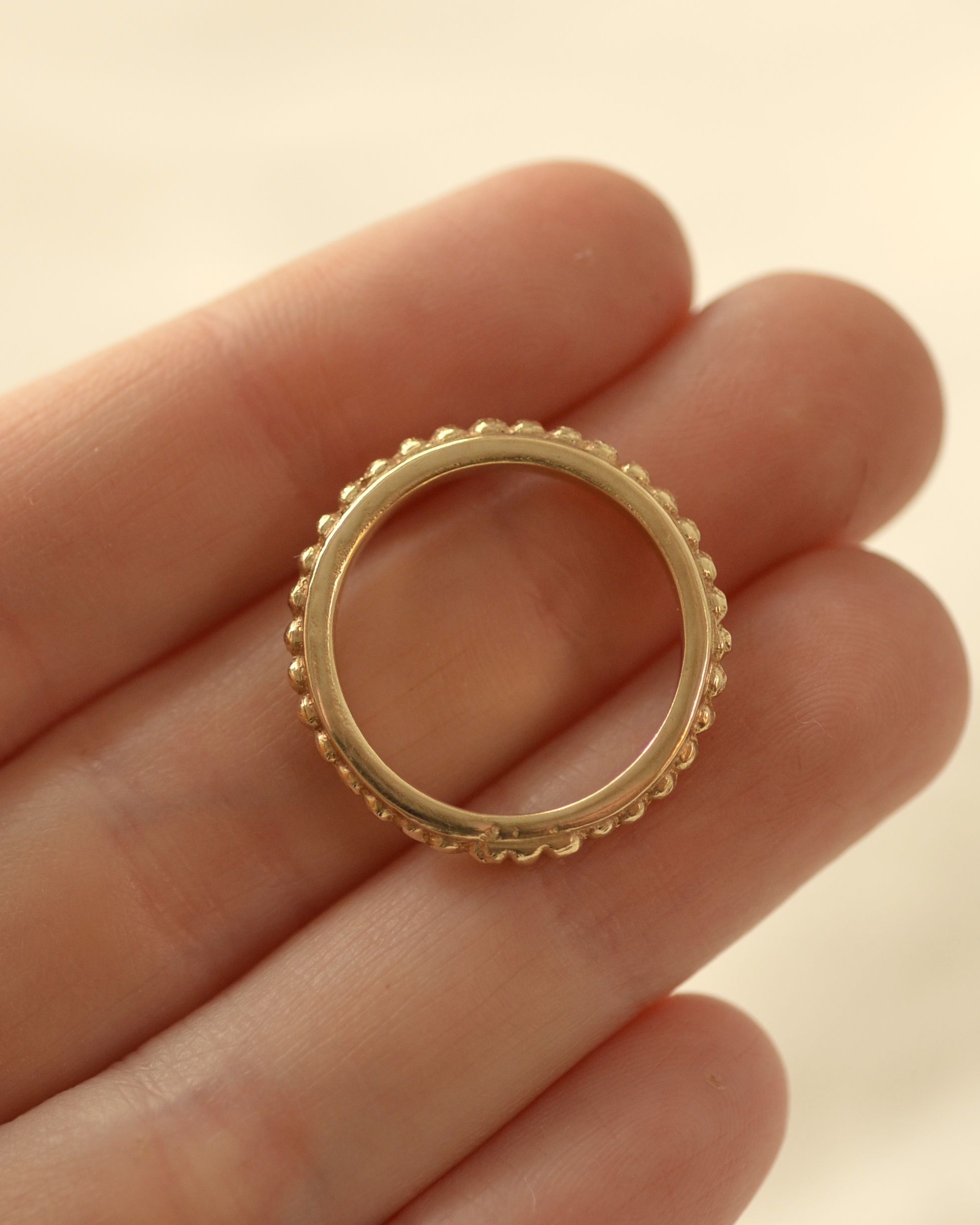 Solid gold grain ring held in hand showing beaded profile