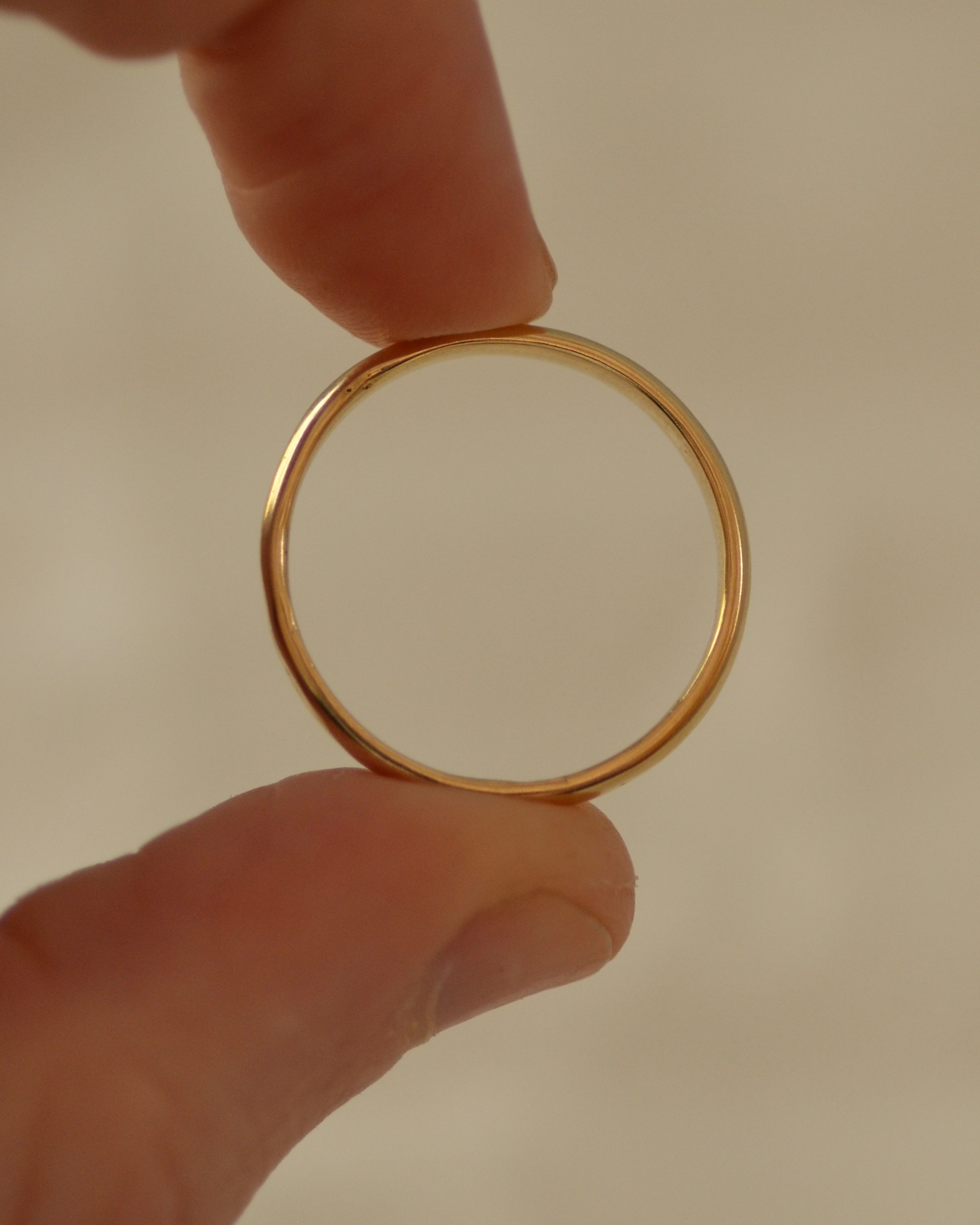 Smooth polished gold ring held between fingers