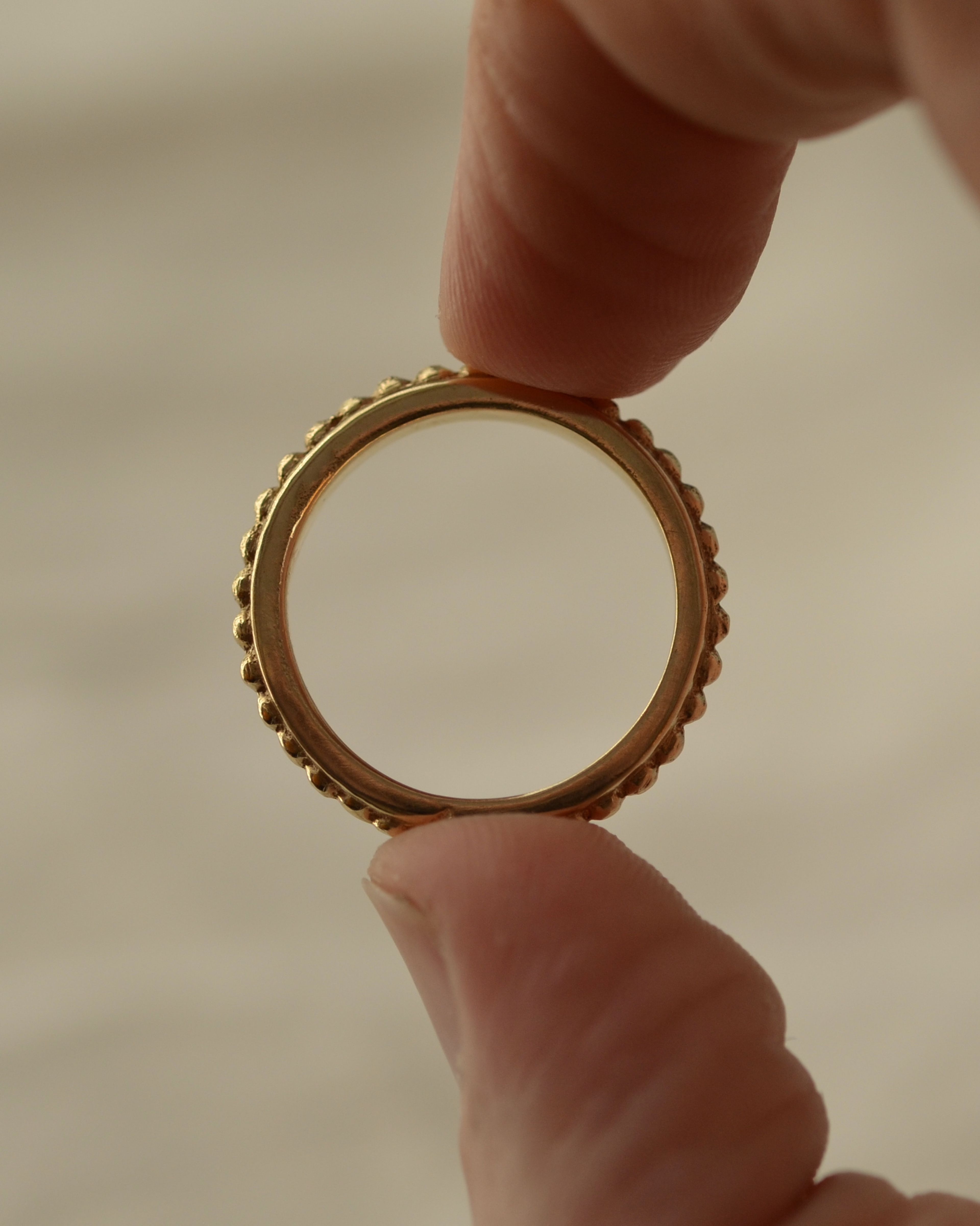 Solid alluvial gold grain ring held between fingers