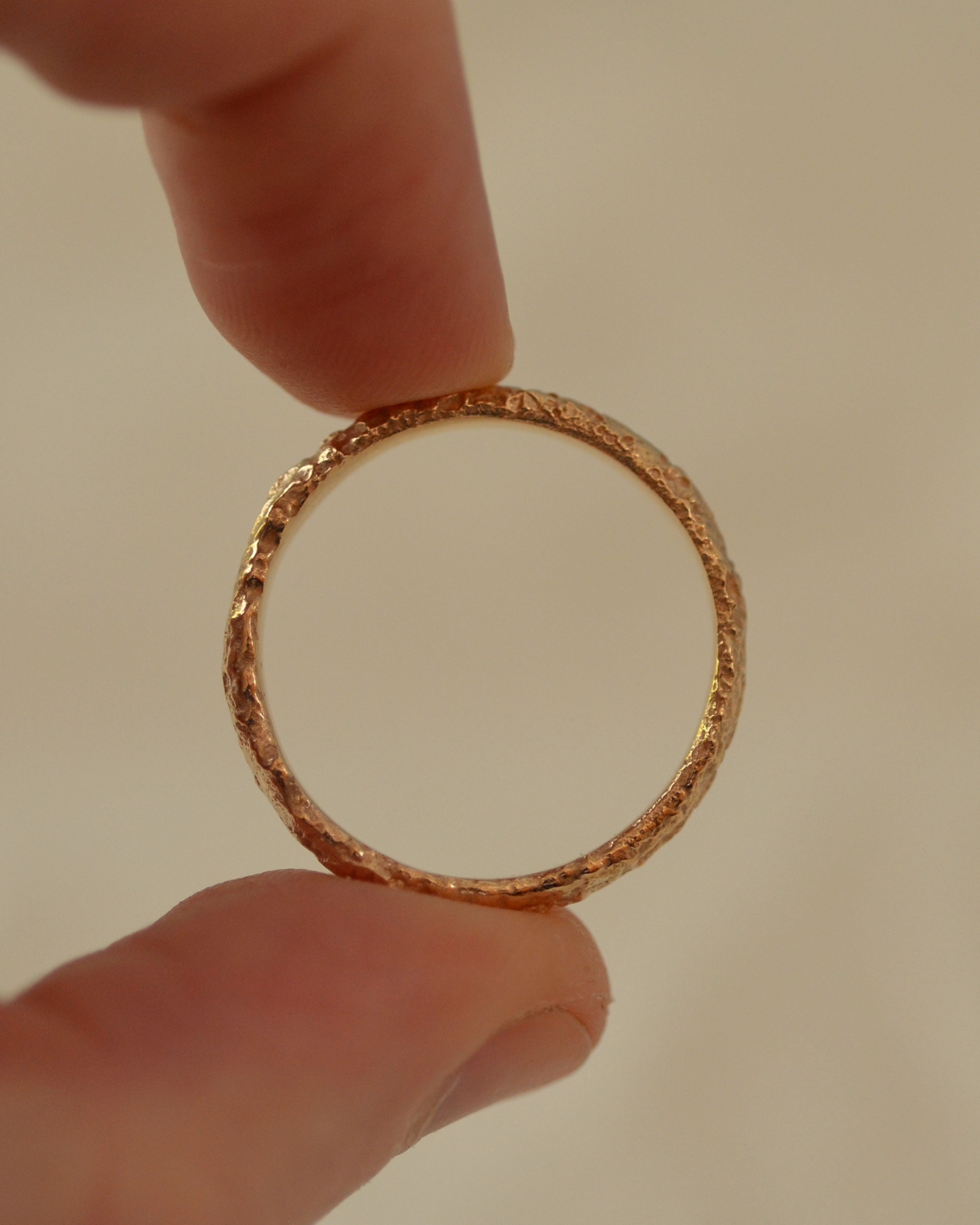 Textured salt gold ring band held between fingers