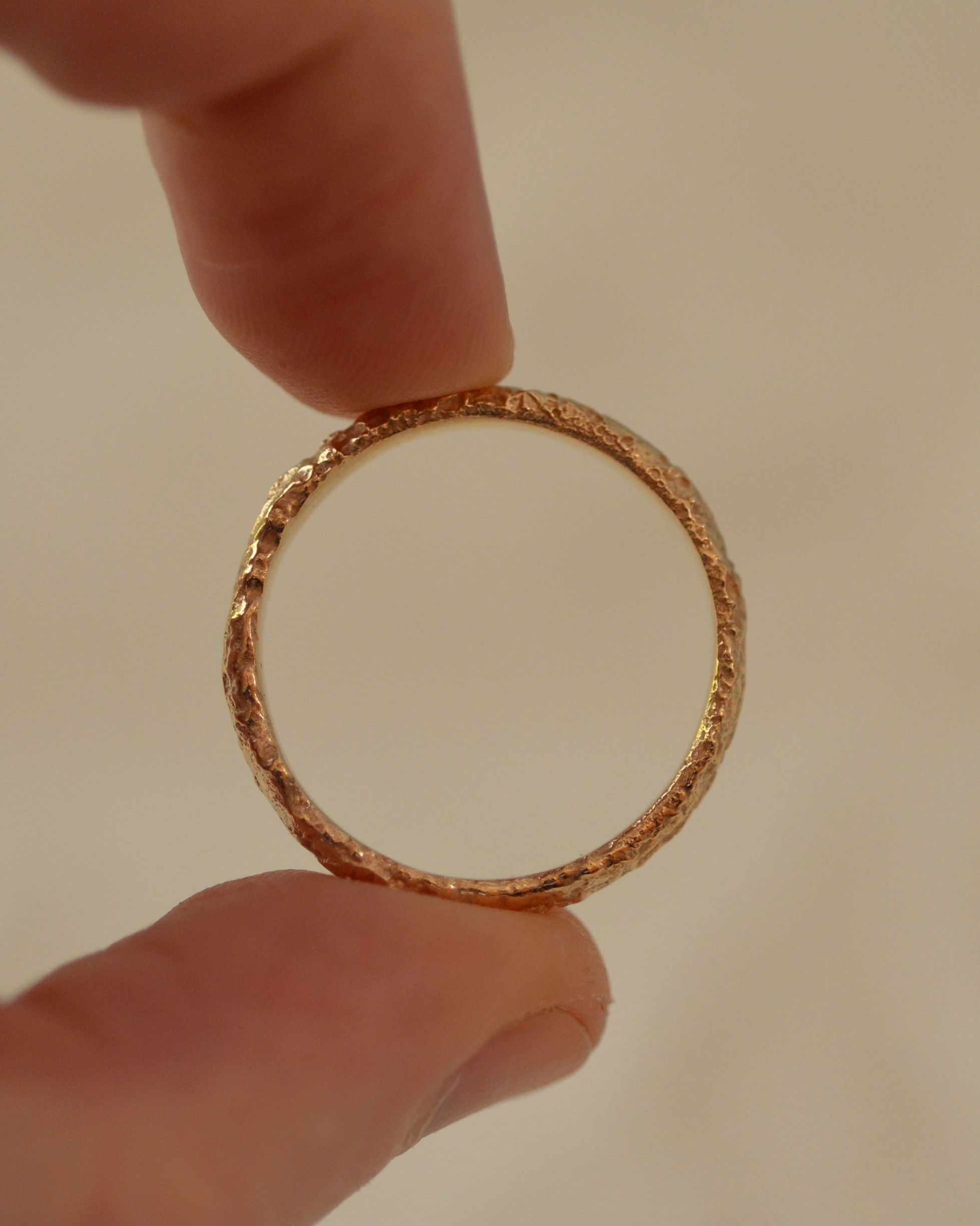 Textured salt gold ring band held between fingers