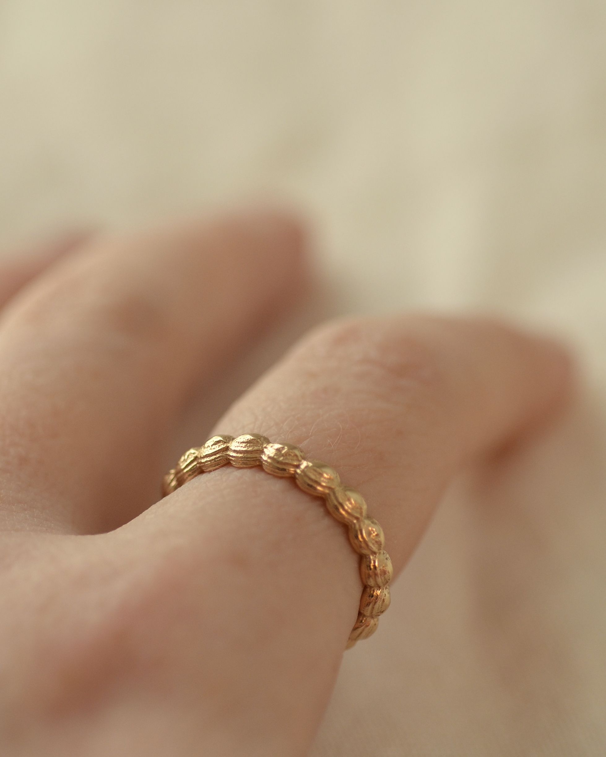 Solid alluvial gold layer ring worn on finger emphasising texture