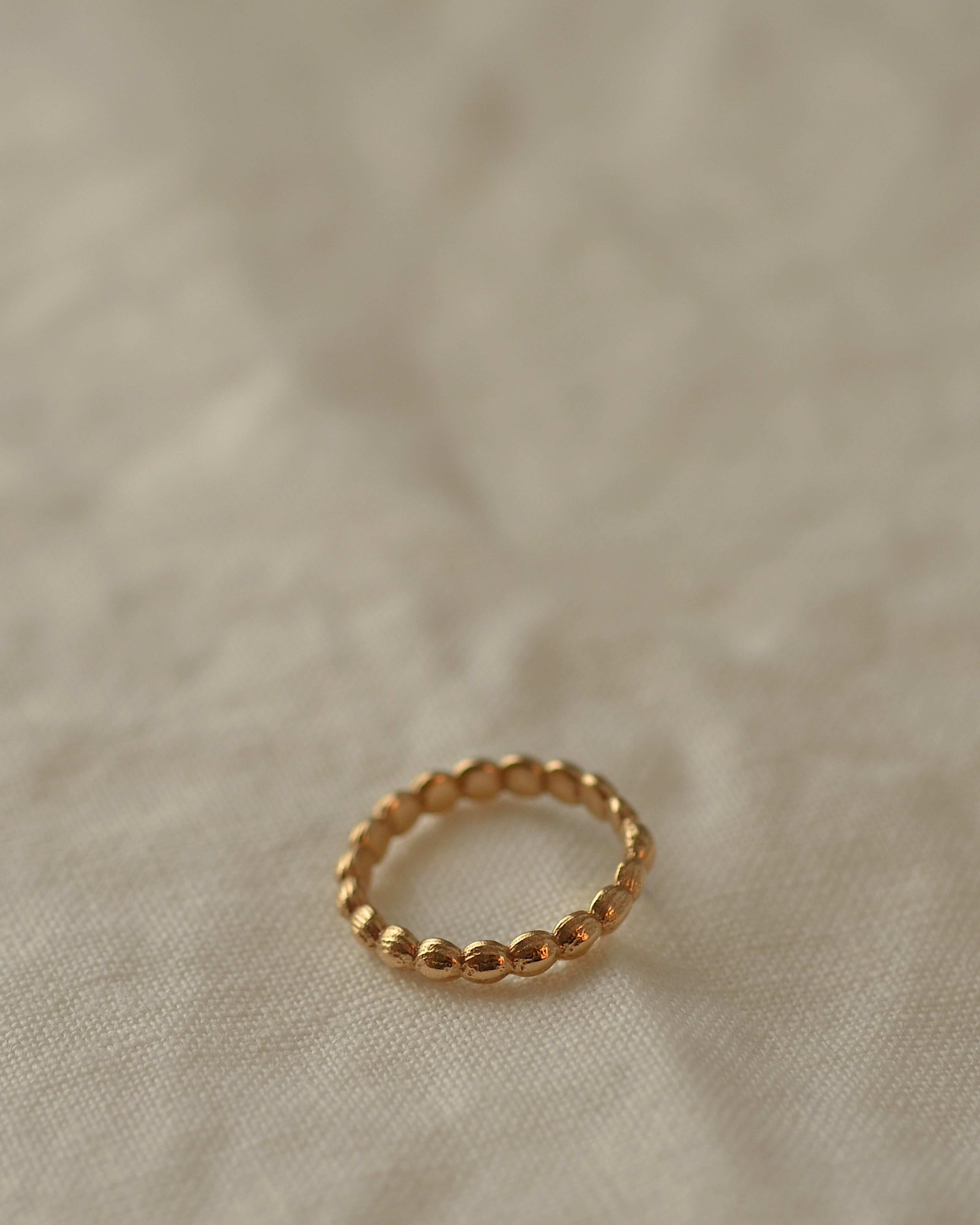 Gold layer ring on cream linen, showing delightful inner ring texture of smooth stones