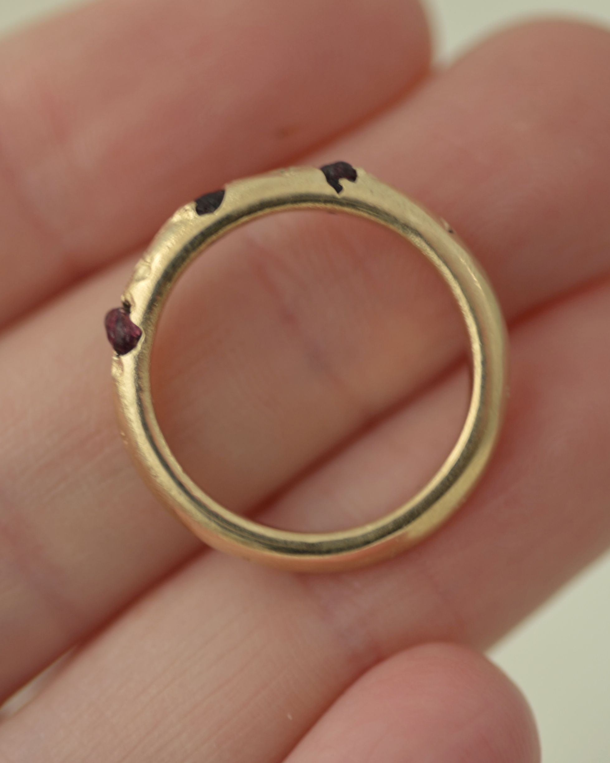 Rough garnet cast in place ring held in hand for scale