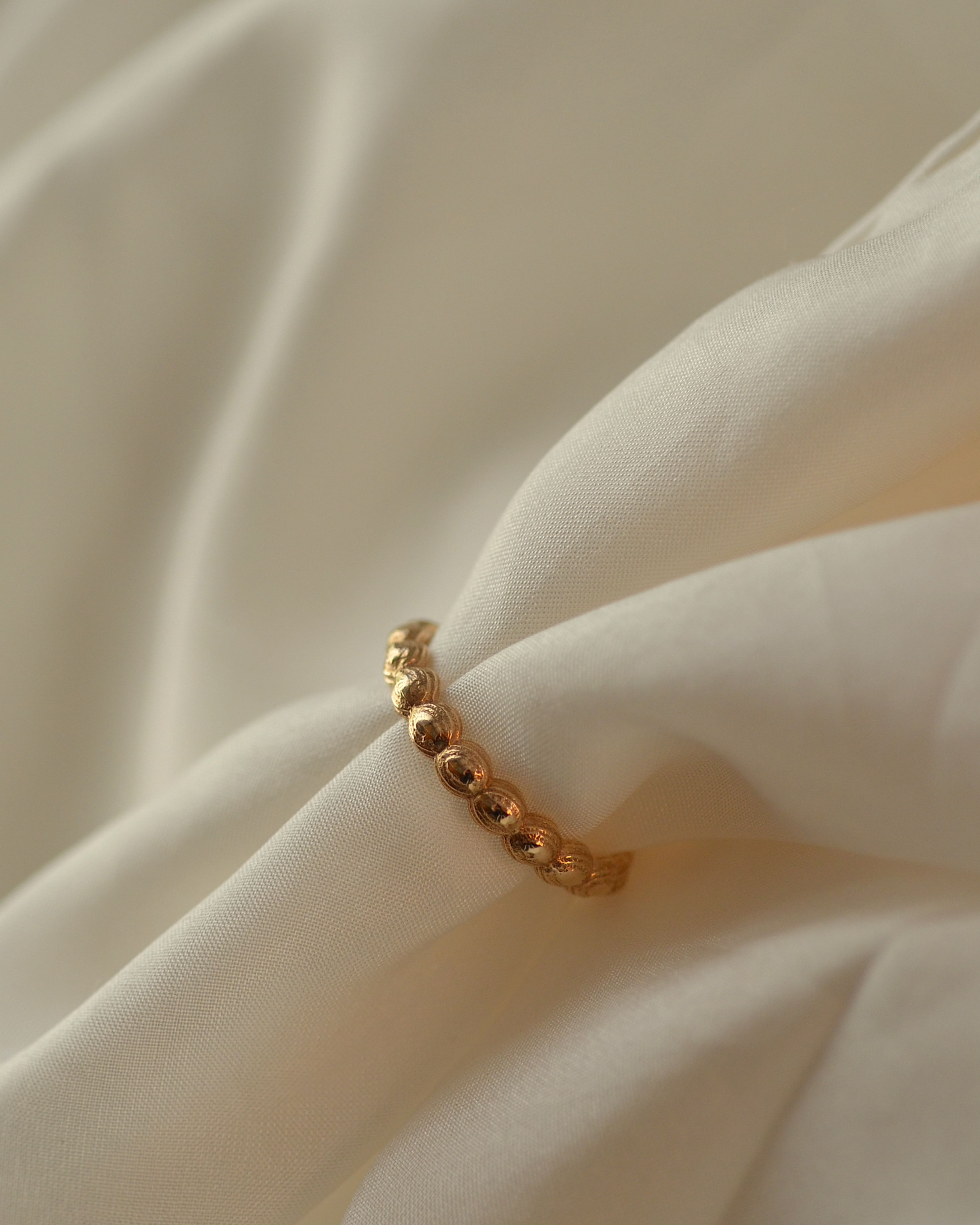 Gold ring of layered stones on cream silk