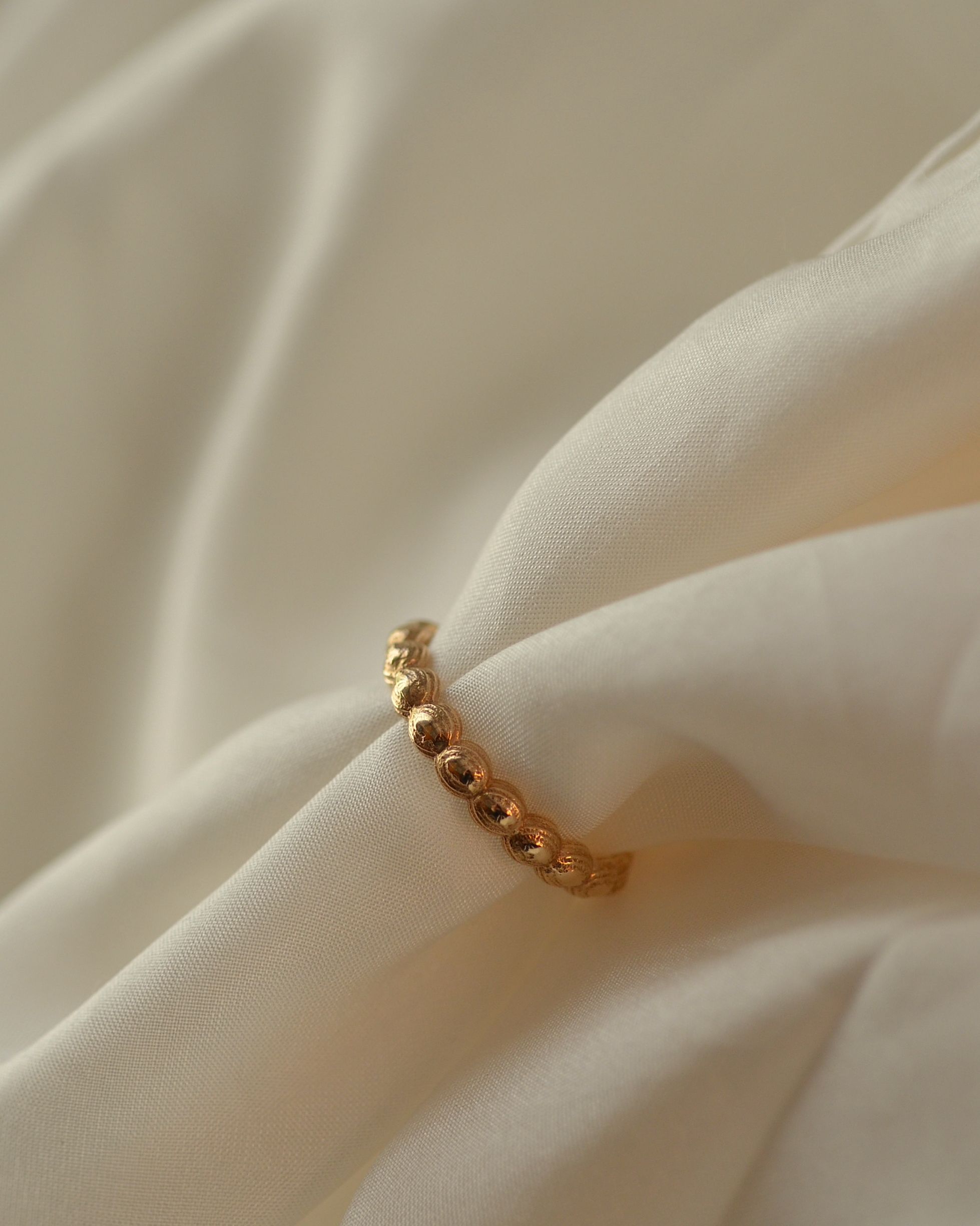 Solid gold layered textural stones ring on cream silk