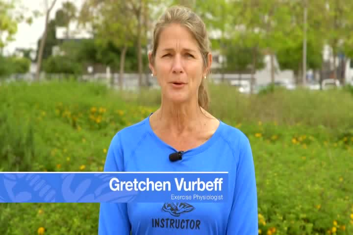 A woman in a blue shirt stands outdoors with greenery in the background. The text on screen identifies her as Gretchen Vurbeff, Exercise Physiologist.