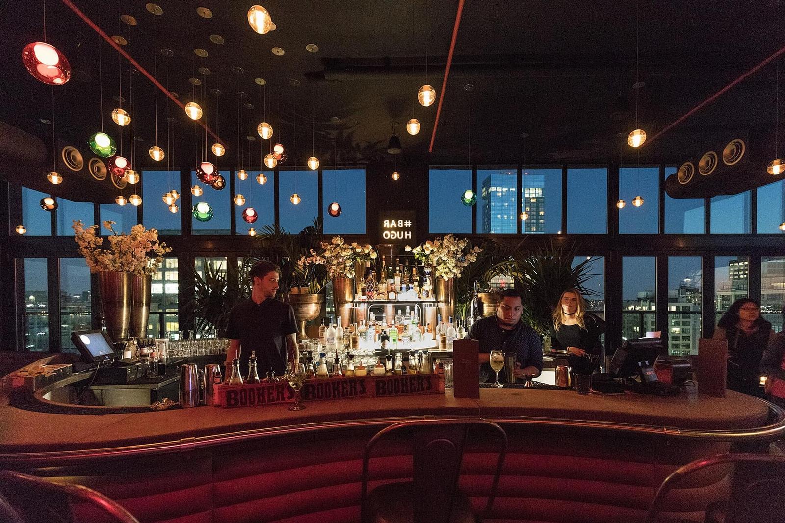 Rooftop bar at dusk with city views and warm pendant lights