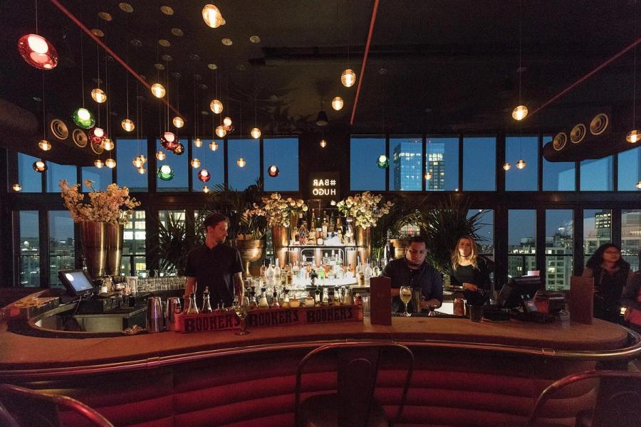 Rooftop bar at dusk with city views and warm pendant lights
