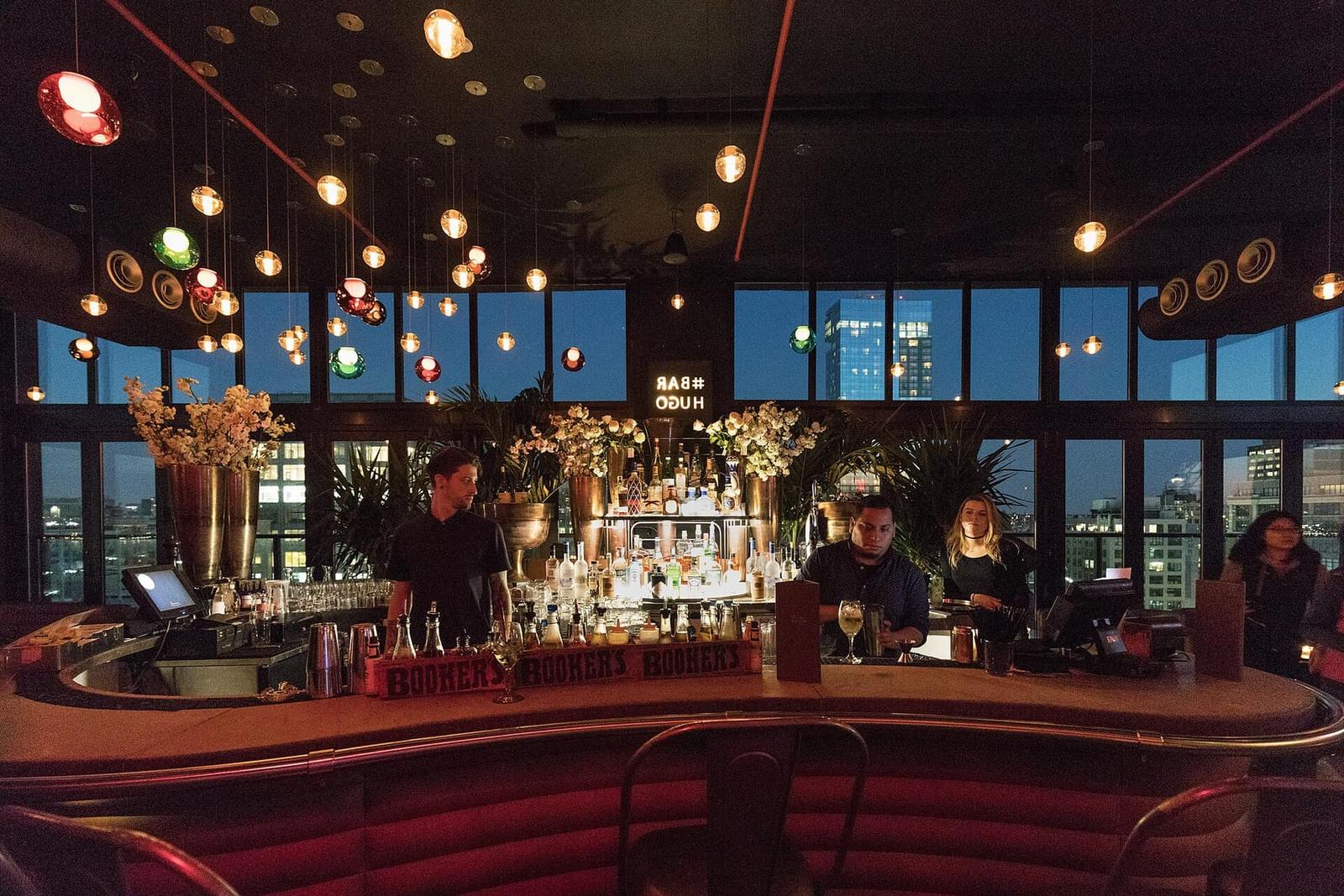 Rooftop bar at dusk with city views and warm pendant lights