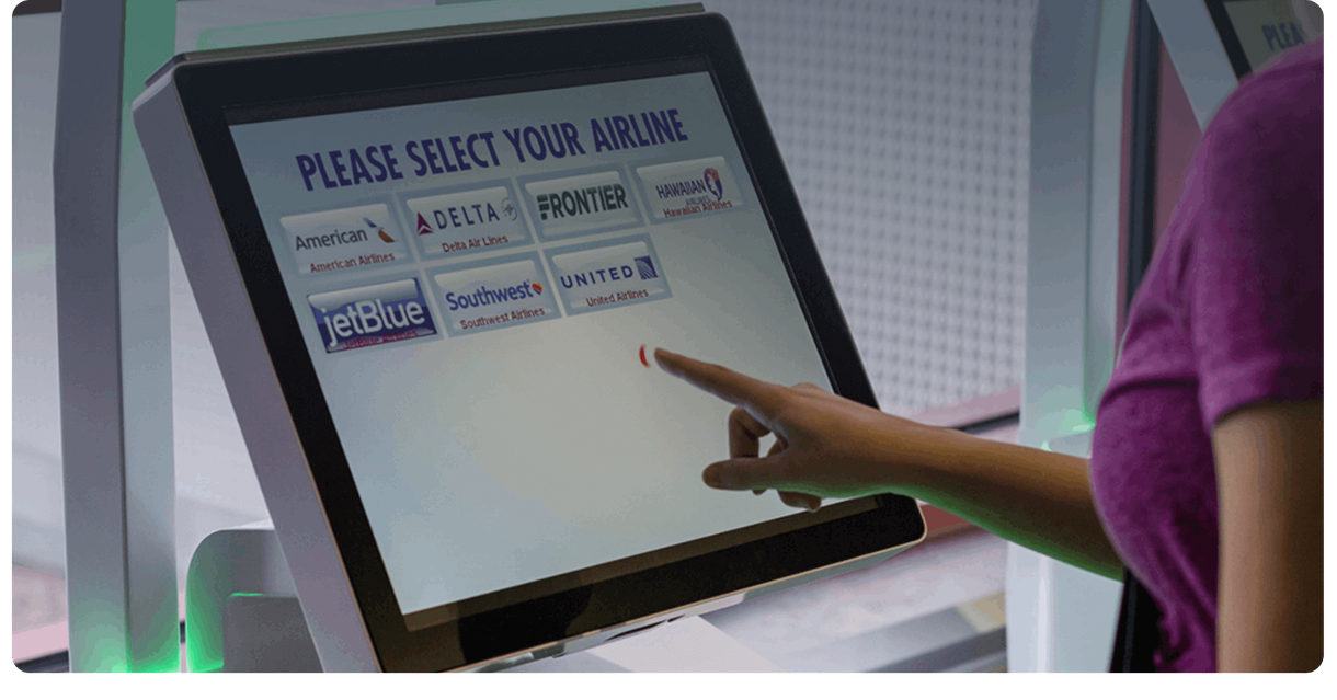 A traveller chooses an airline on a check-in kiosk