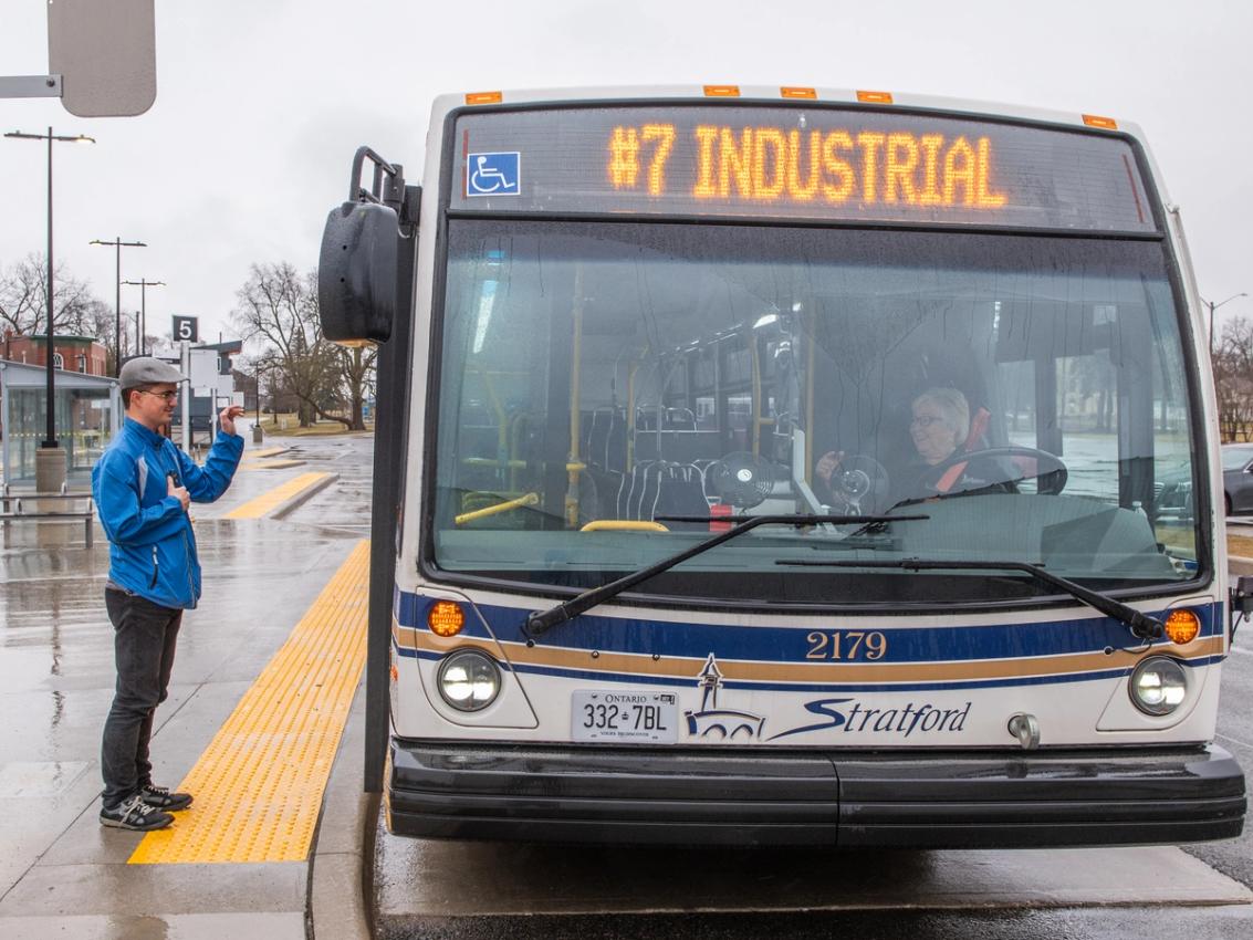 A rider waits as a Stratford Transit bus pulls up to the stop