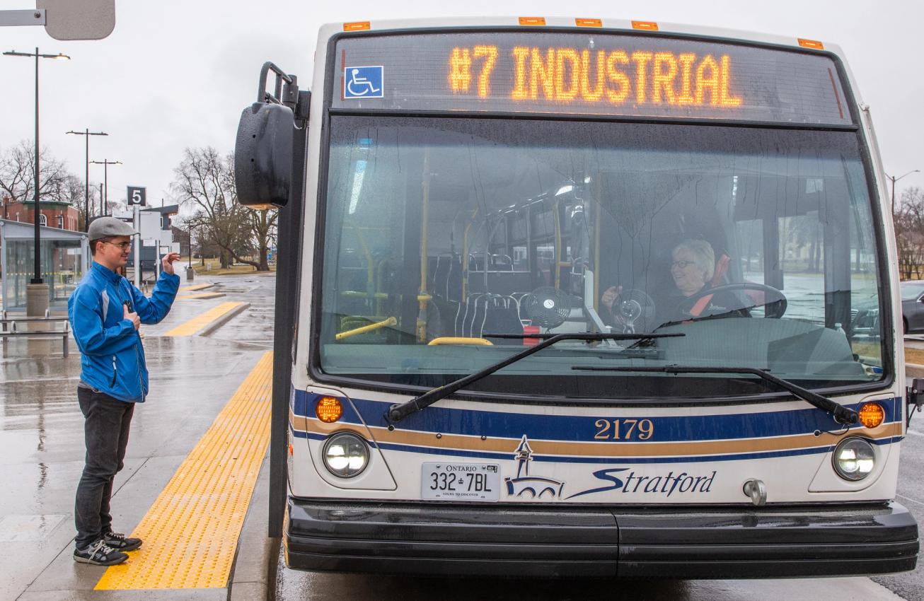 A rider waits as a Stratford Transit bus pulls up to the stop
